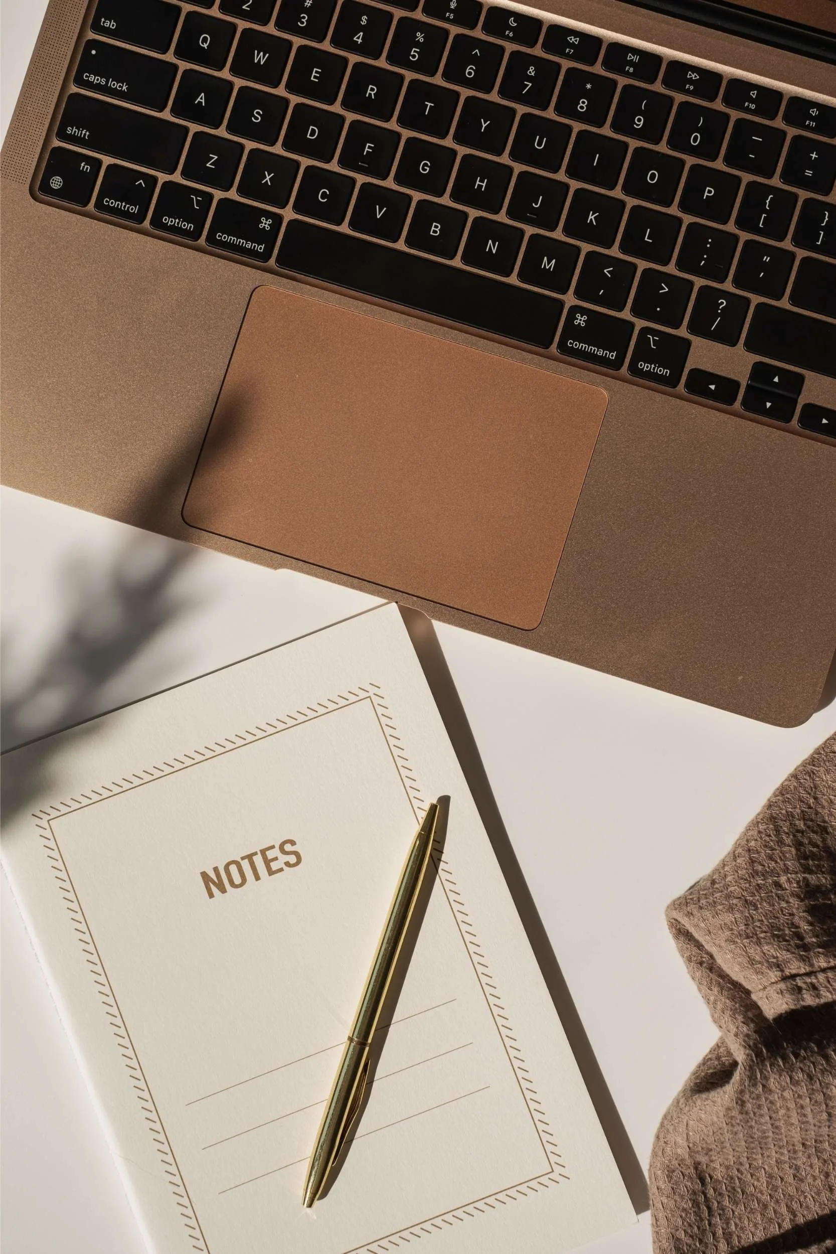 laptop trackpad with notebook and pen on desk