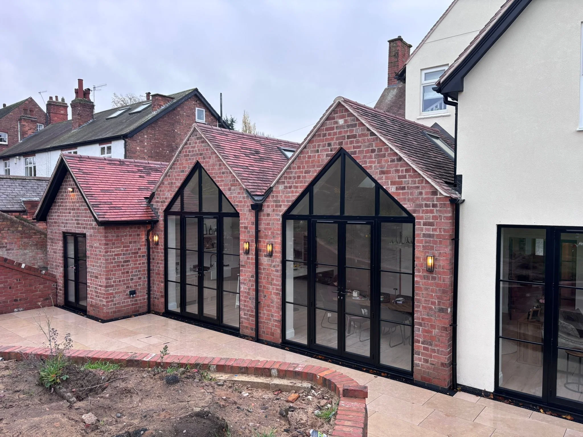 Brick rear extension with pitched gables and black framed glazed doors at a family home in Woodthorpe Nottingham built by Butterworth & Martin