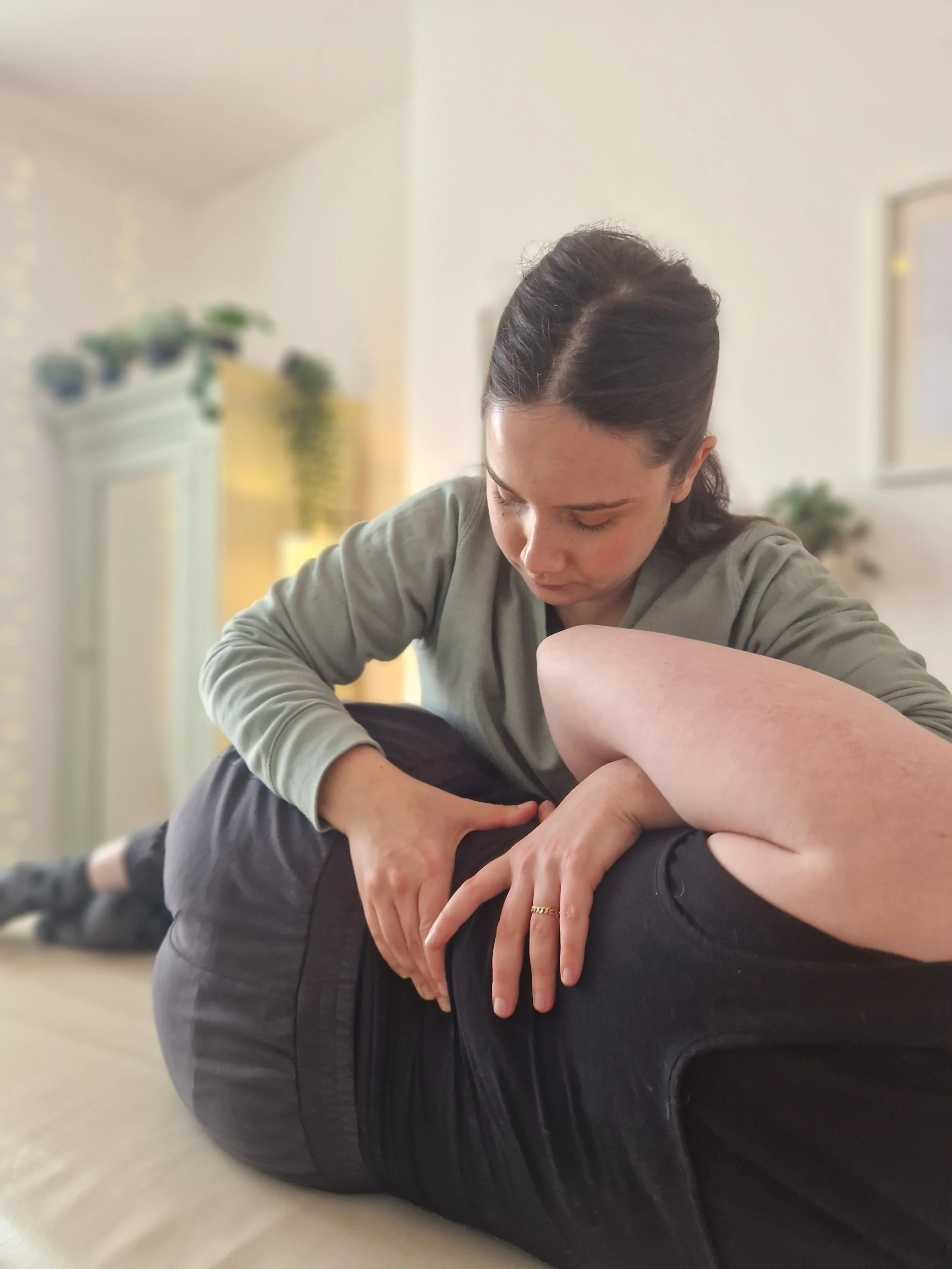 A female Osteopath providing a treatment to a patient lying on their side on a treatment couch, focusing on the person's back.