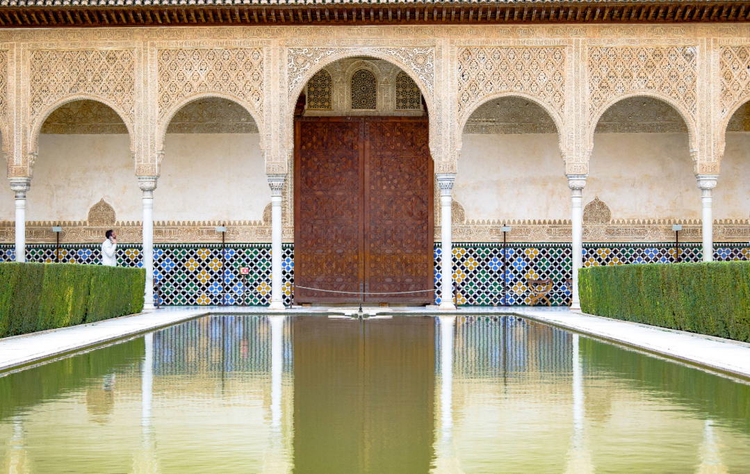 A man on the phone, while taking a leisurely stroll through the Nasrid Palaces.
