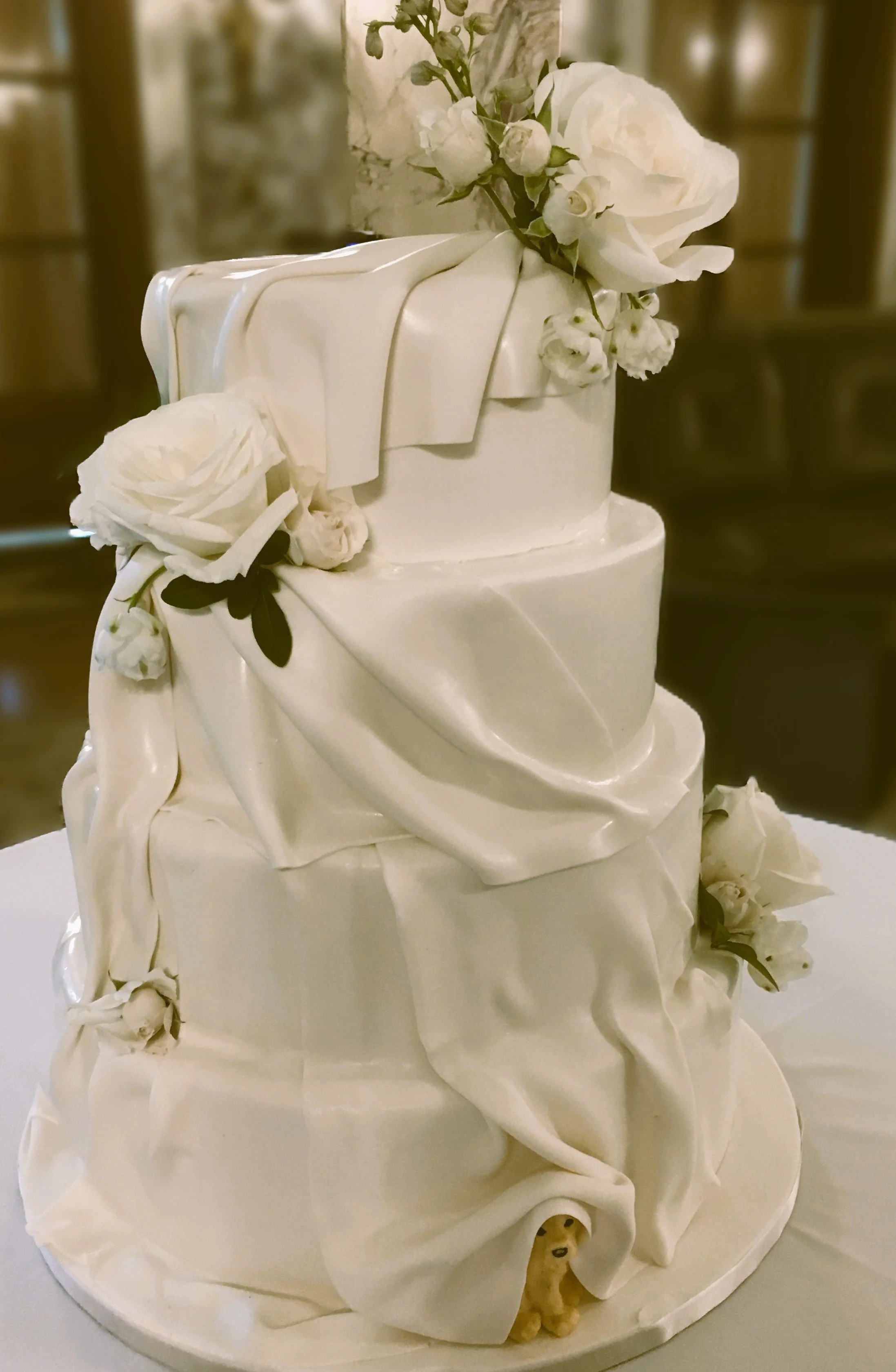 Wedding cake with the couple's dog hiding under one of the frosting folds at the bottom of the cake. Delicious too. 