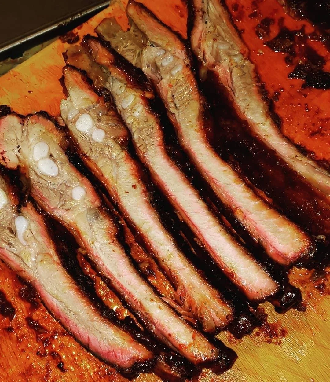 a stack of barbecued ribs on a flat top grill