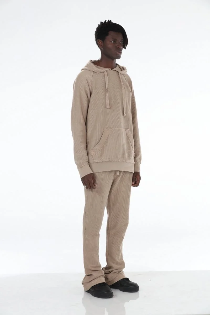 Young man wearing a light blue hoodie and matching sweatpants, standing against a white background.