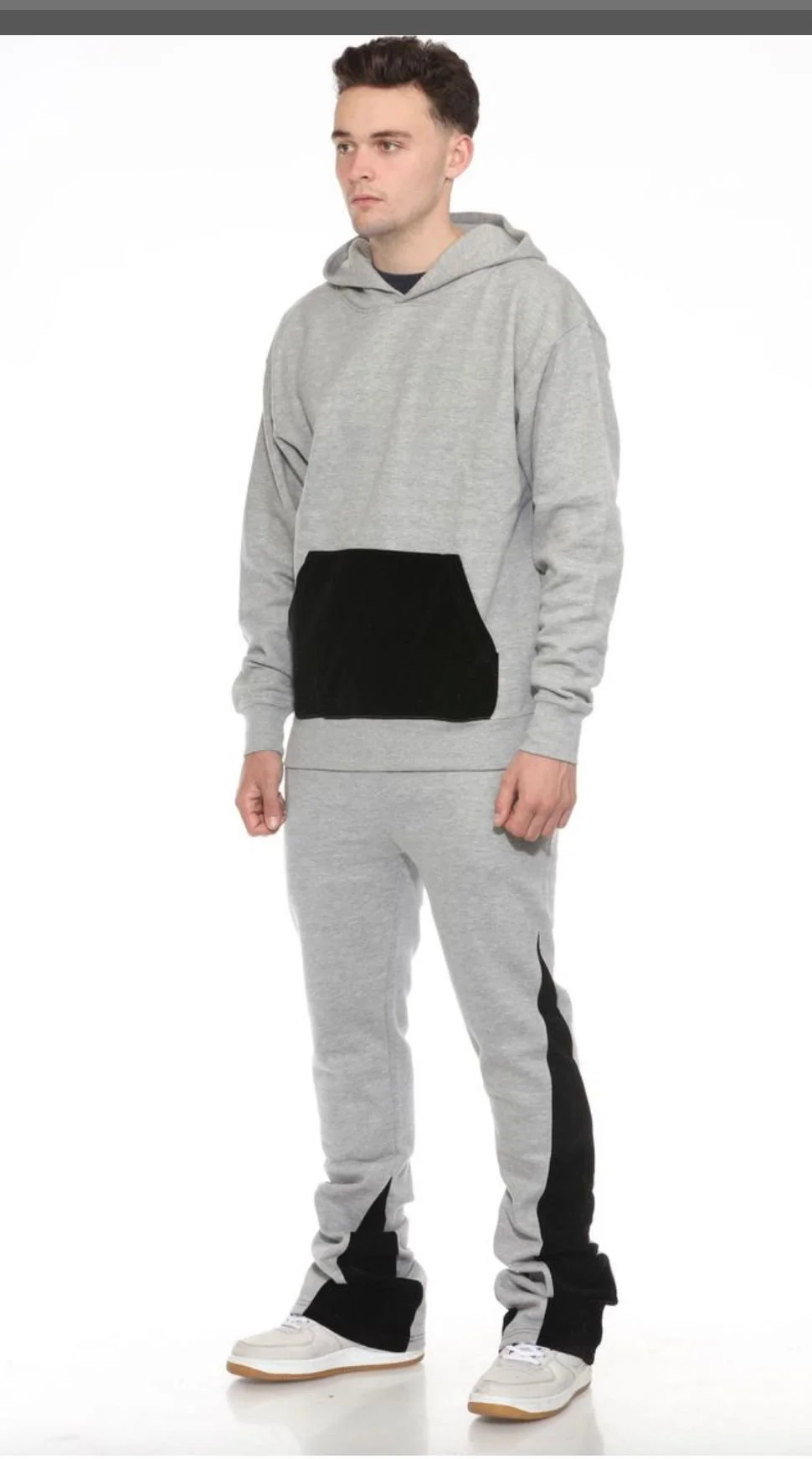 Young man wearing a light blue hoodie and matching sweatpants, standing against a white background.