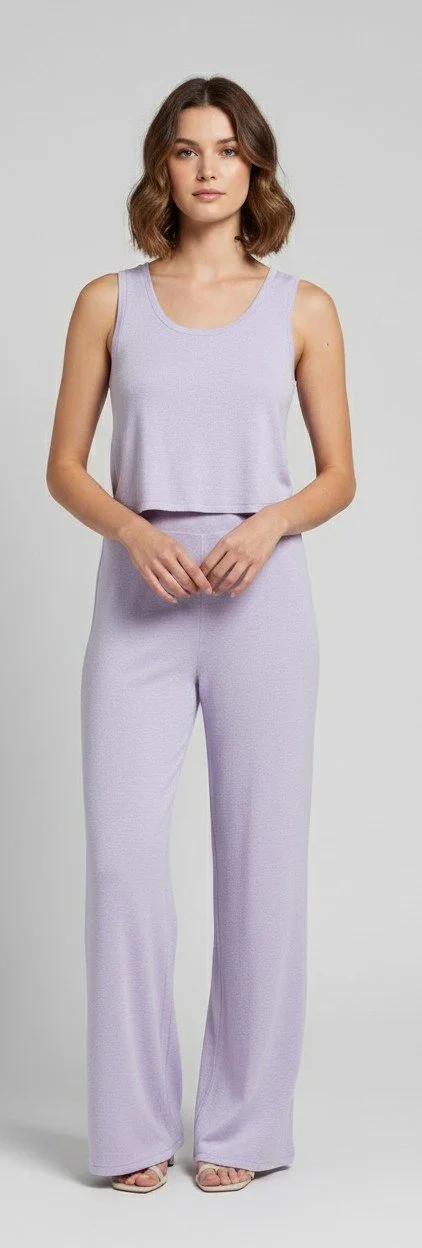 Woman wearing a light blue cropped hoodie and matching sweatpants standing barefoot against a plain gray background.