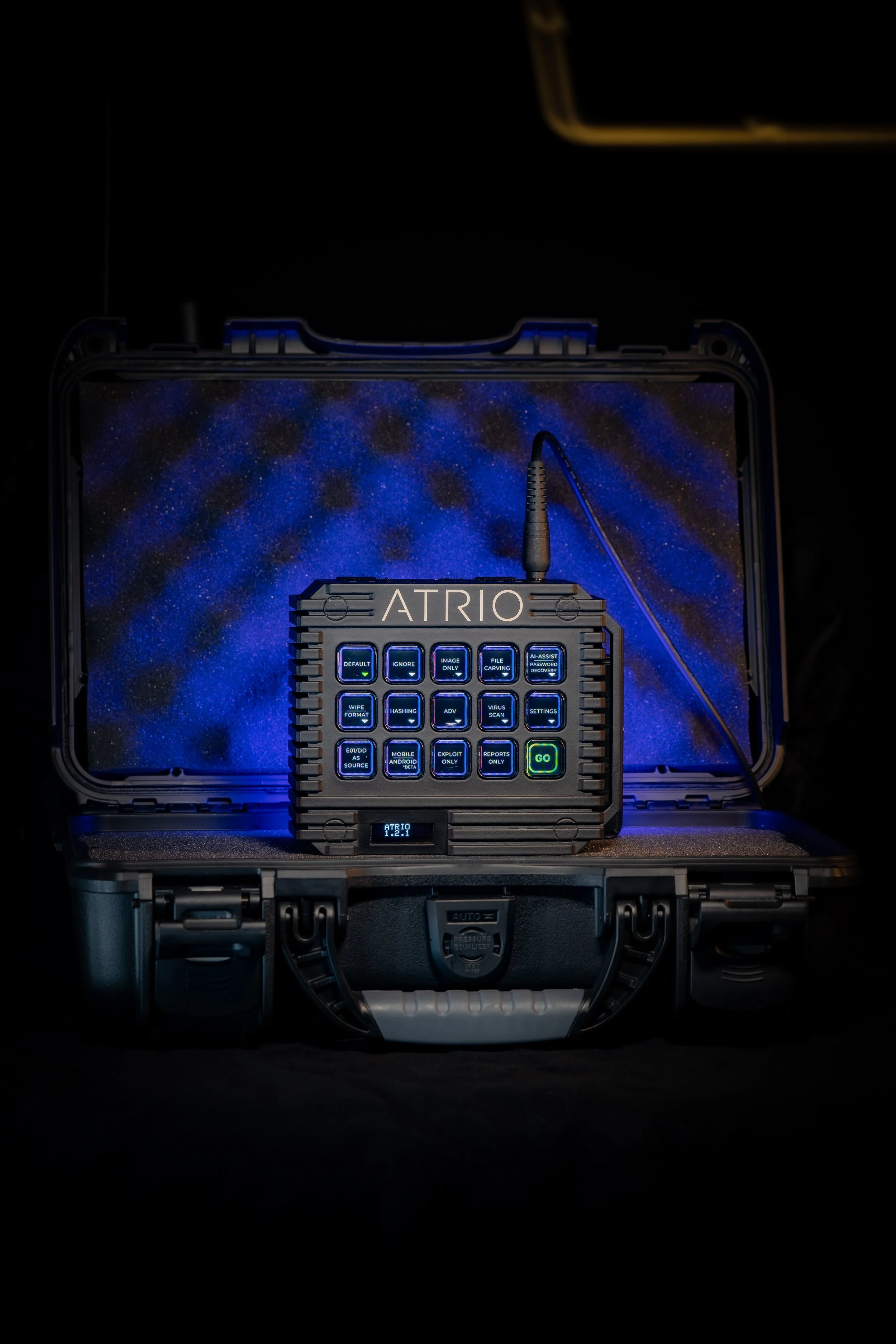 A black electronic device labeled 'ATRIO' with multiple buttons and a small screen, placed inside a black case with blue background imagery.
