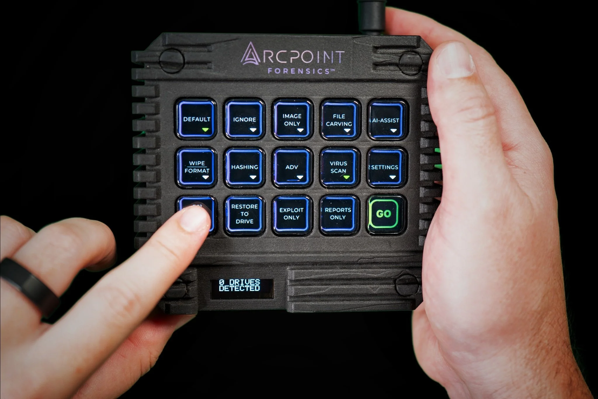A forensic computer device with a grid of blue-lit buttons and a small screen displaying '0 DRIVES DETECTED.' A person's hands are interacting with the device, with one finger pressing the "RESTORE TO DRIVE" button and the other hand holding the device.