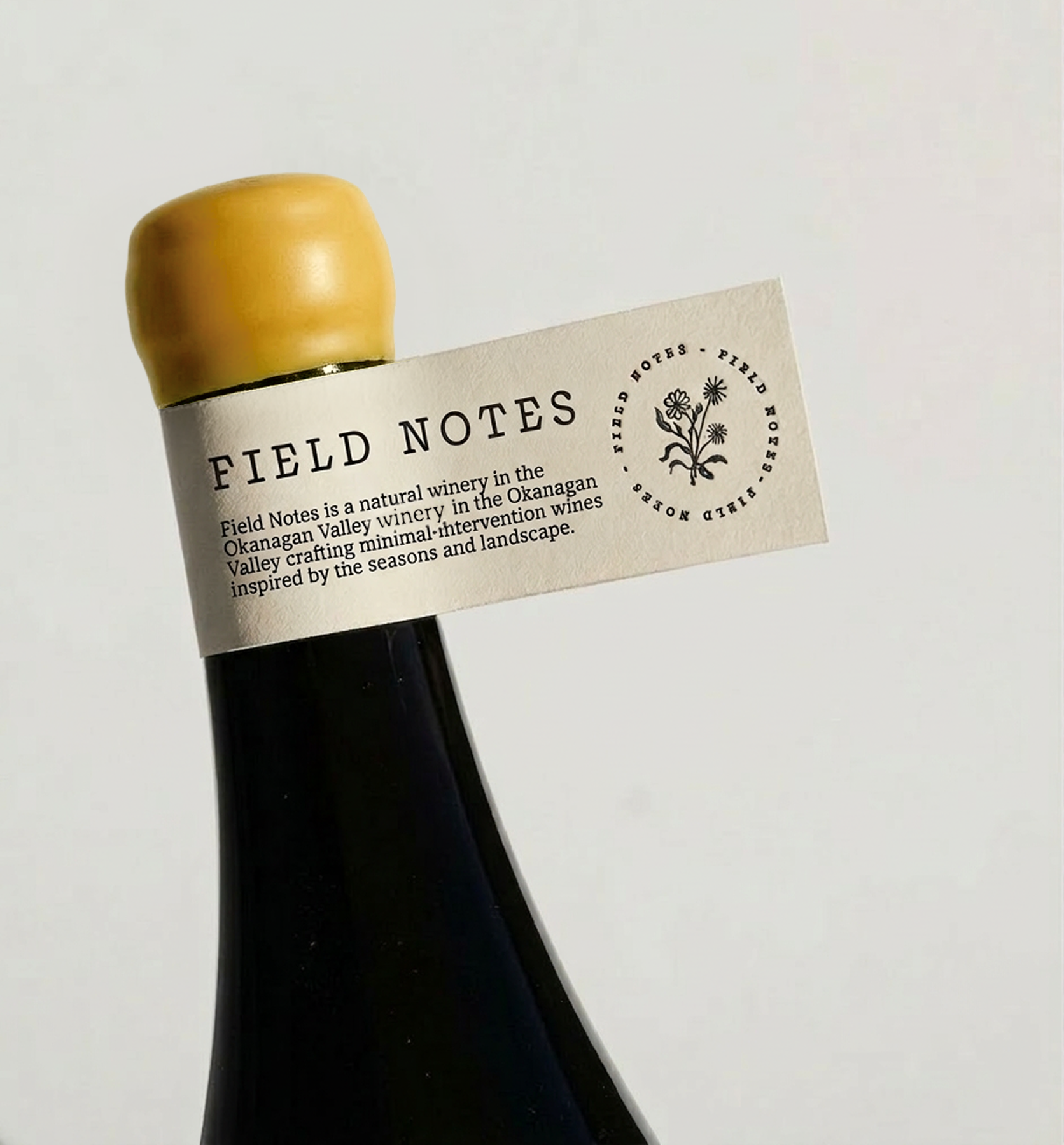 A wine bottle with a yellow cap and a label that reads 'Field Notes' on a plain white background.