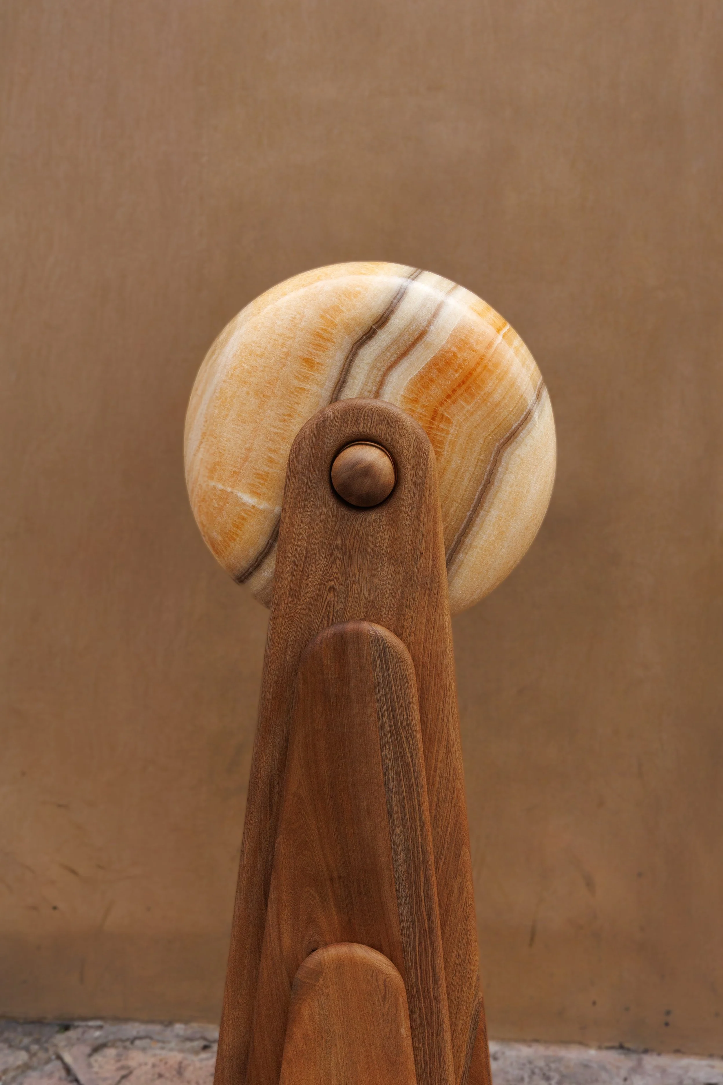 Close-up of a wooden and marble sculpture with rounded shapes and natural tones.