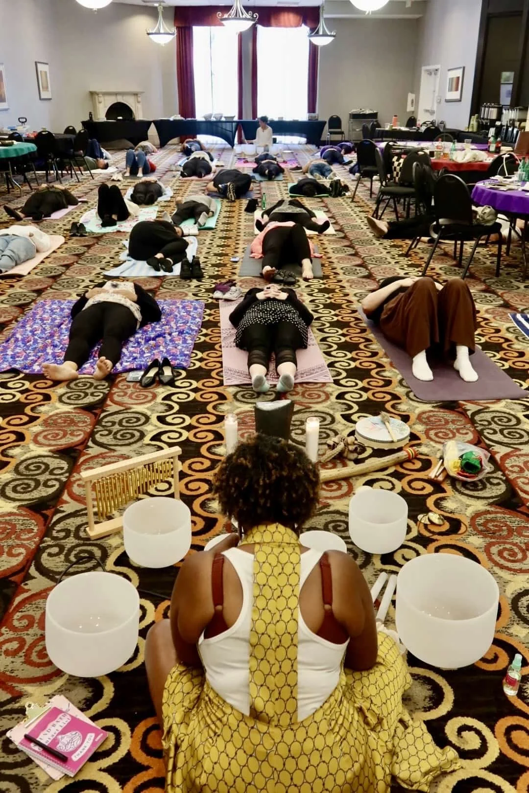 A group sound healing session with participants lying on mats.