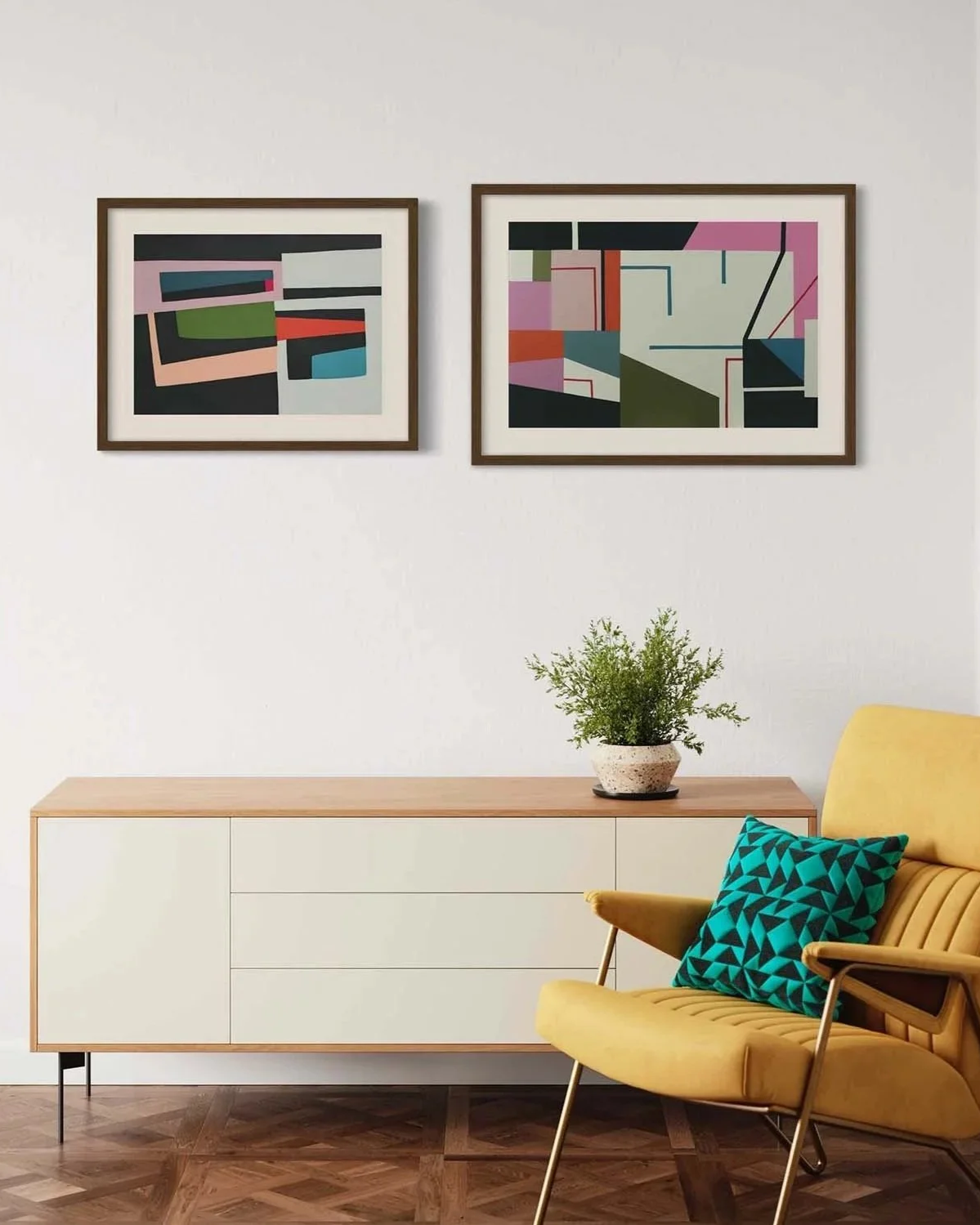 A modern living room with two abstract art pieces hanging above a white sideboard. A green potted plant is placed on the sideboard. There is a yellow armchair with a teal geometric patterned pillow next to the sideboard.