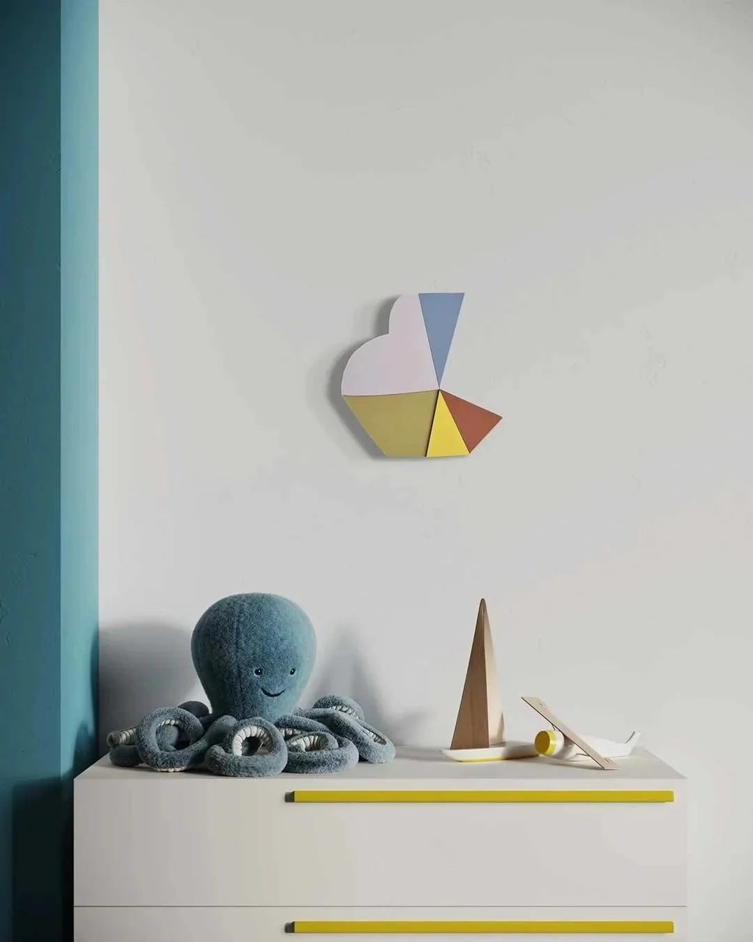 Decorative objects on a white dresser, including a plush octopus toy and abstract wooden sculptures, with a colorful geometric wall art piece above.