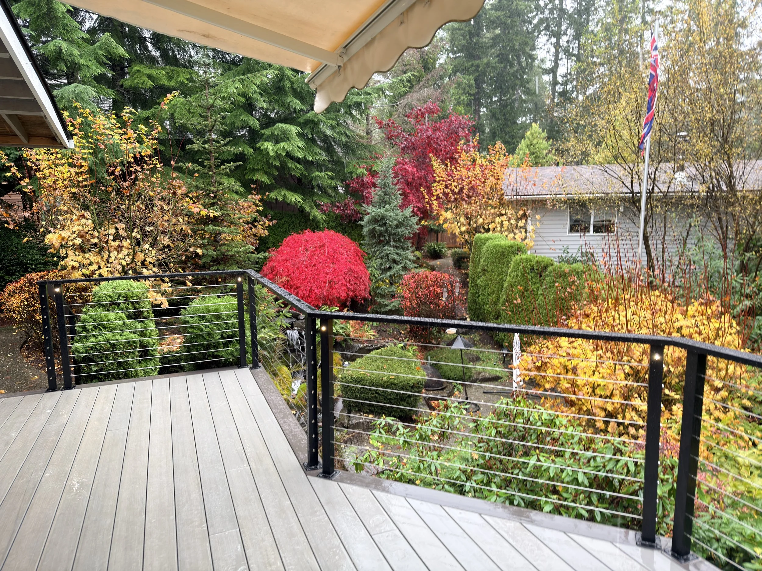 Custom railing installed on a backyard patio overlooking a manicured multi-colored landscape.