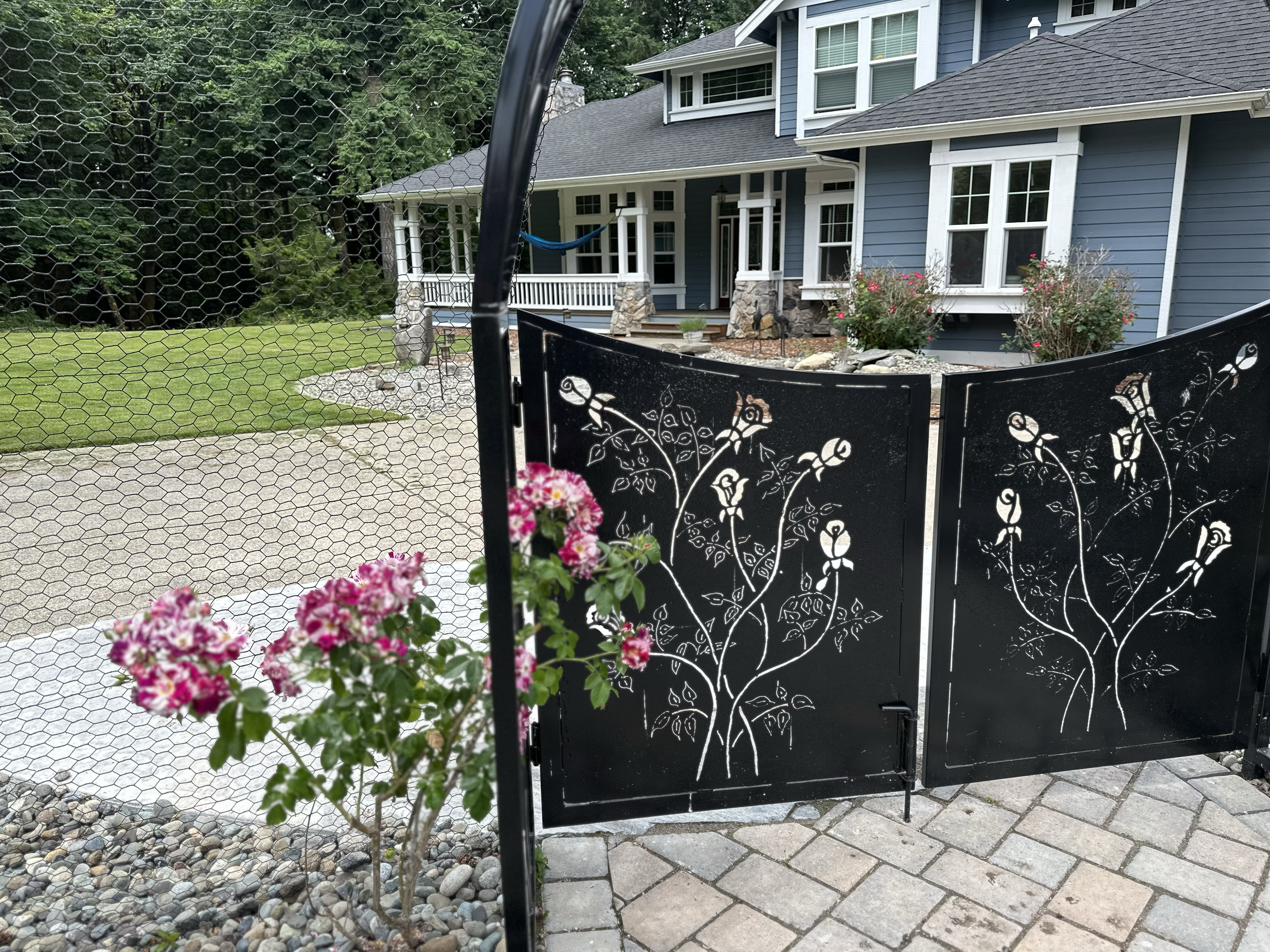 A custom front yard entryway with a rose-cutout swinging front gate.