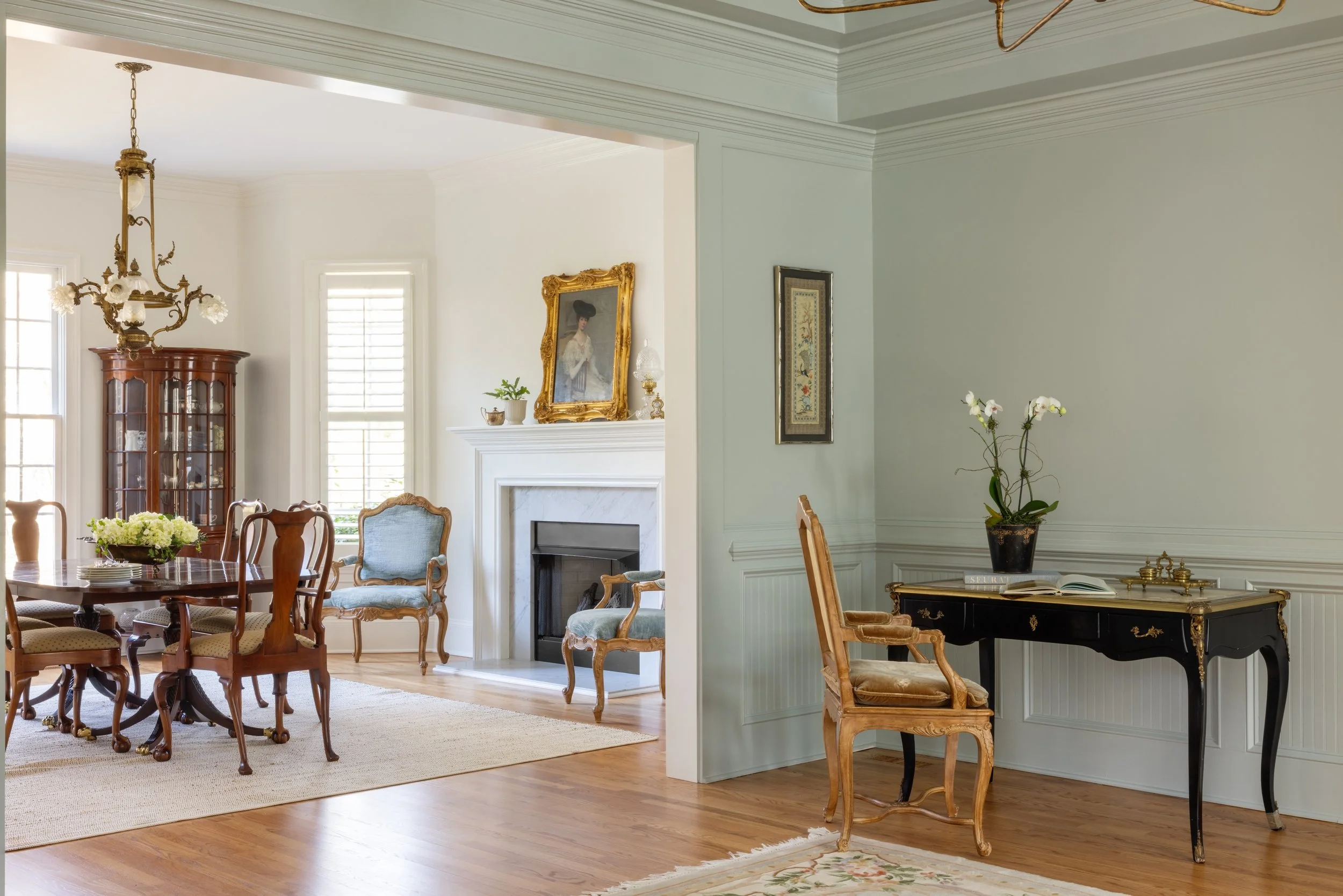 Elegant living room with white walls, wooden furniture, a fireplace, and decorative paintings.