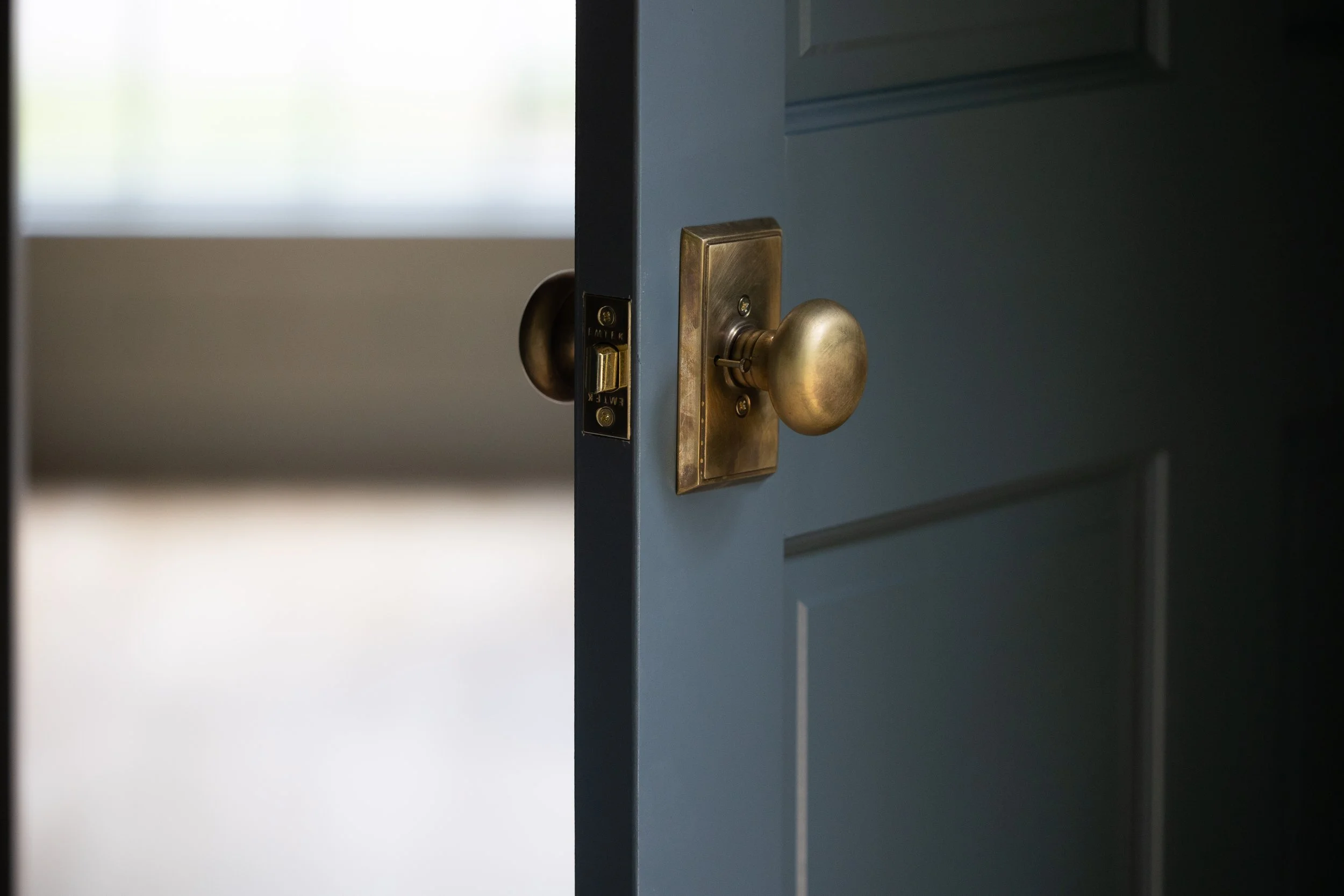 A partially open blue door with a brass doorknob and latch.