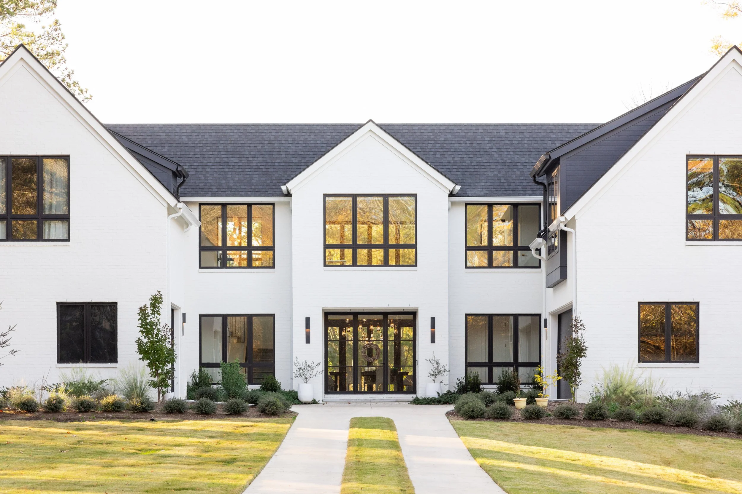 Luxury custom home front elevation by Will Johnson Building Company in the Triangle NC with white brick exterior, symmetrical architecture, black windows, manicured lawn, and upscale residential design details
