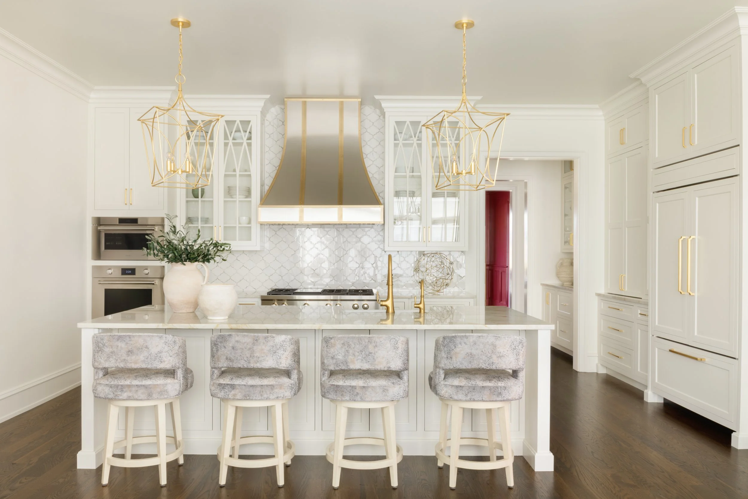 White kitchen interior of a luxury custom home by Will Johnson Building Company in the Triangle NC featuring large island, gold fixtures, pendant lighting, and custom cabinetry