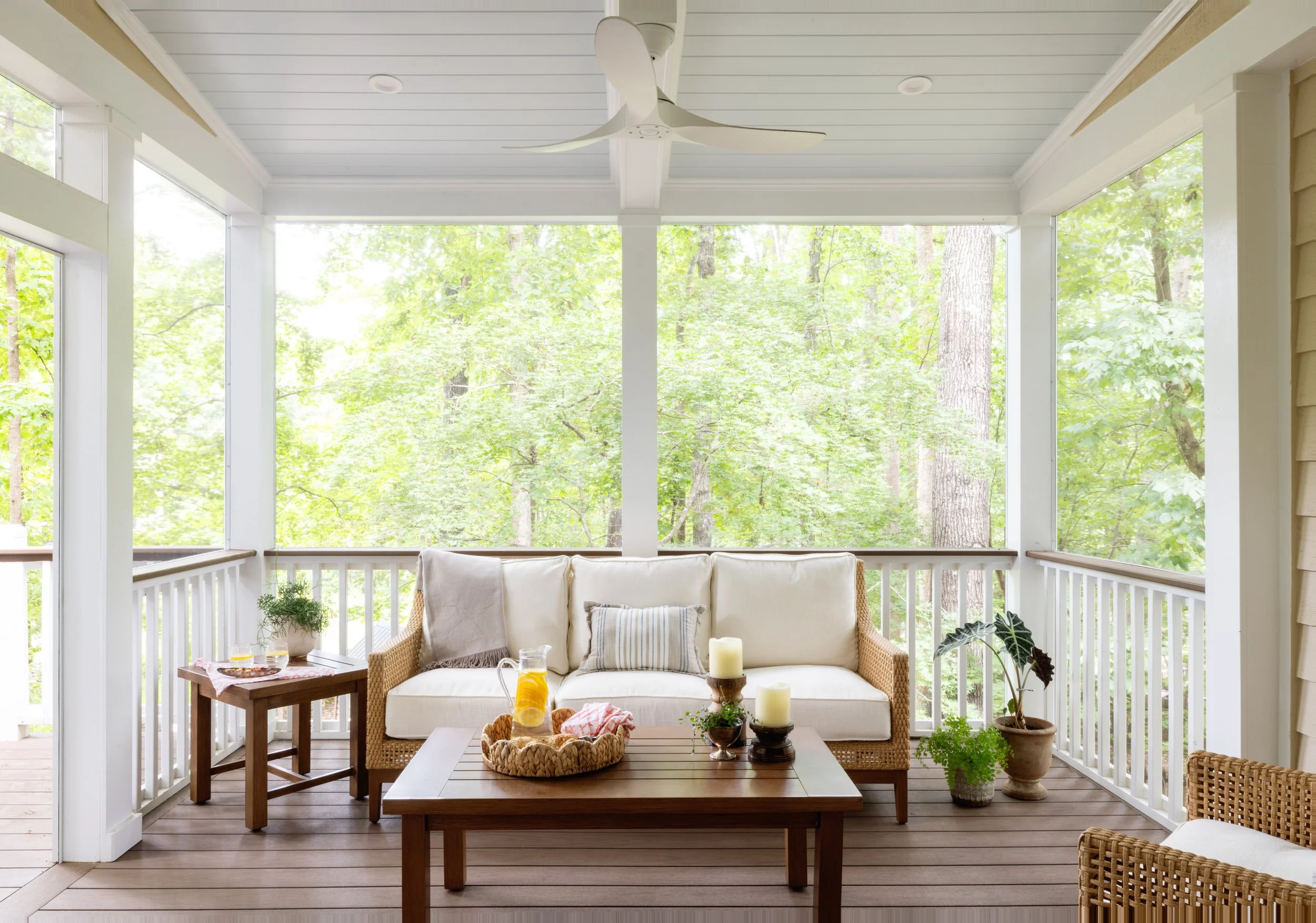 Covered porch with comfortable seating overlooking a wooded landscape at a modern transitional custom home