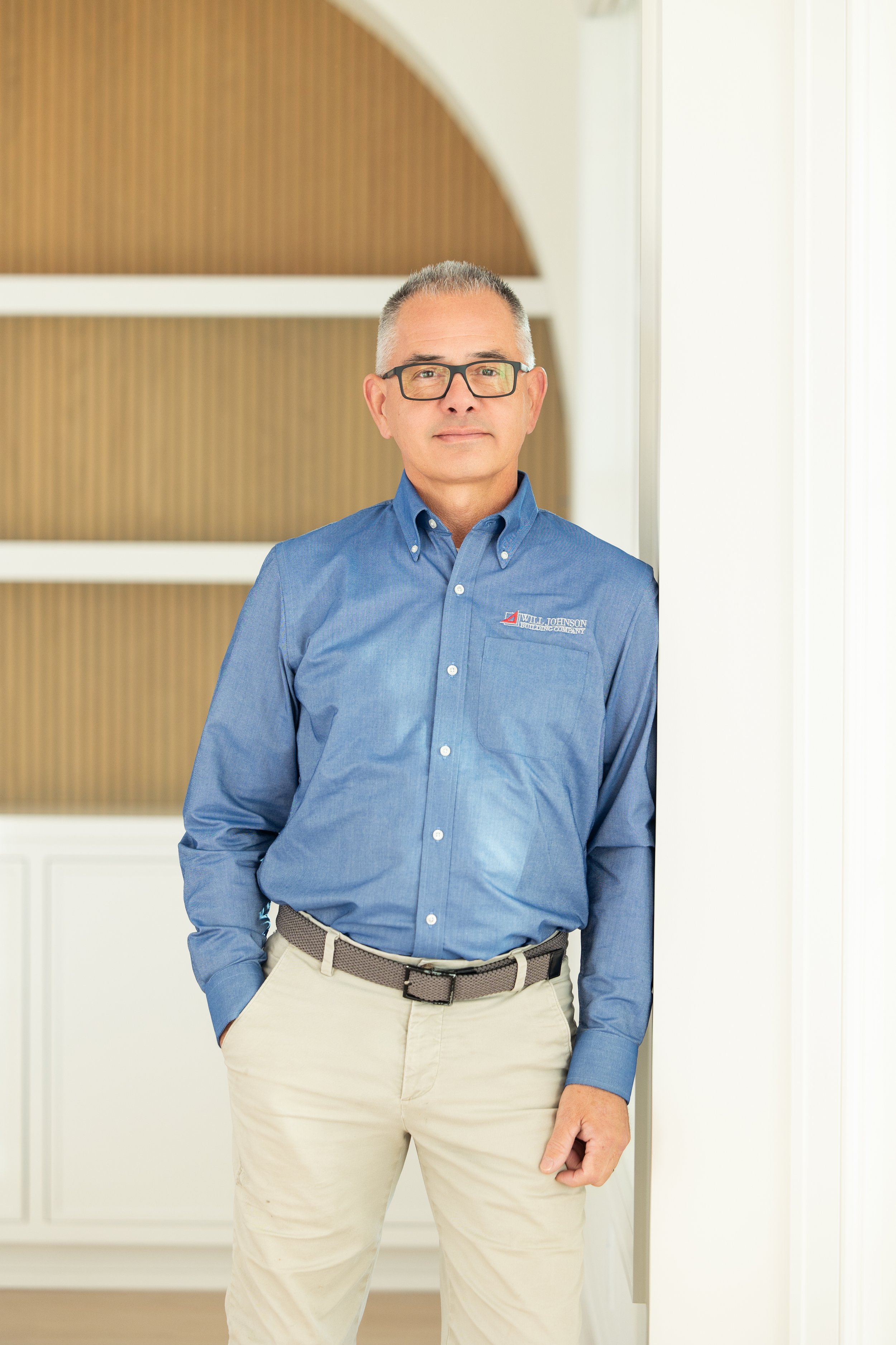 Man in outdoor construction site holding blueprints on a rock.