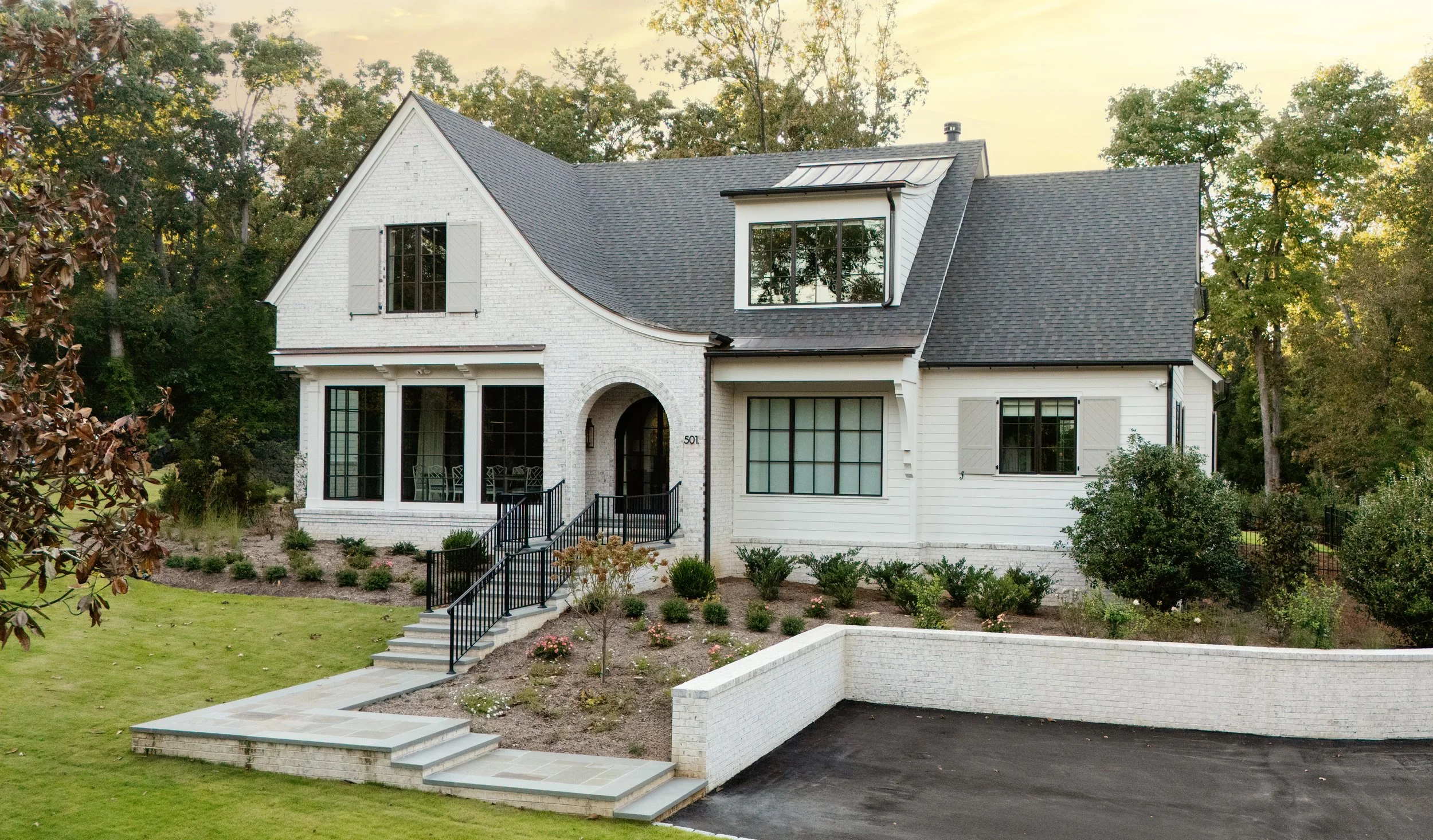 Modern transitional custom home with painted brick exterior on a wooded homesite
