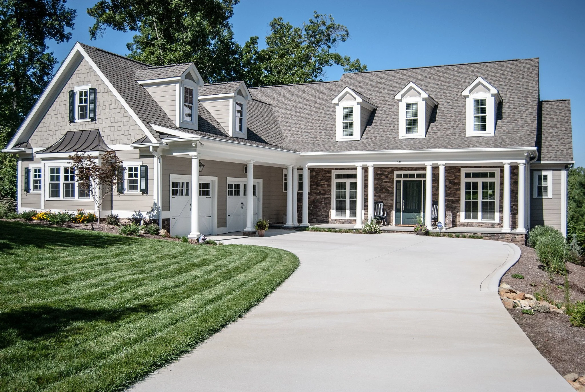 Timeless luxury custom home in the Triangle featuring covered porches, dormer windows, stone accents, and classic exterior detailing designed for long-term livability and lasting curb appeal.