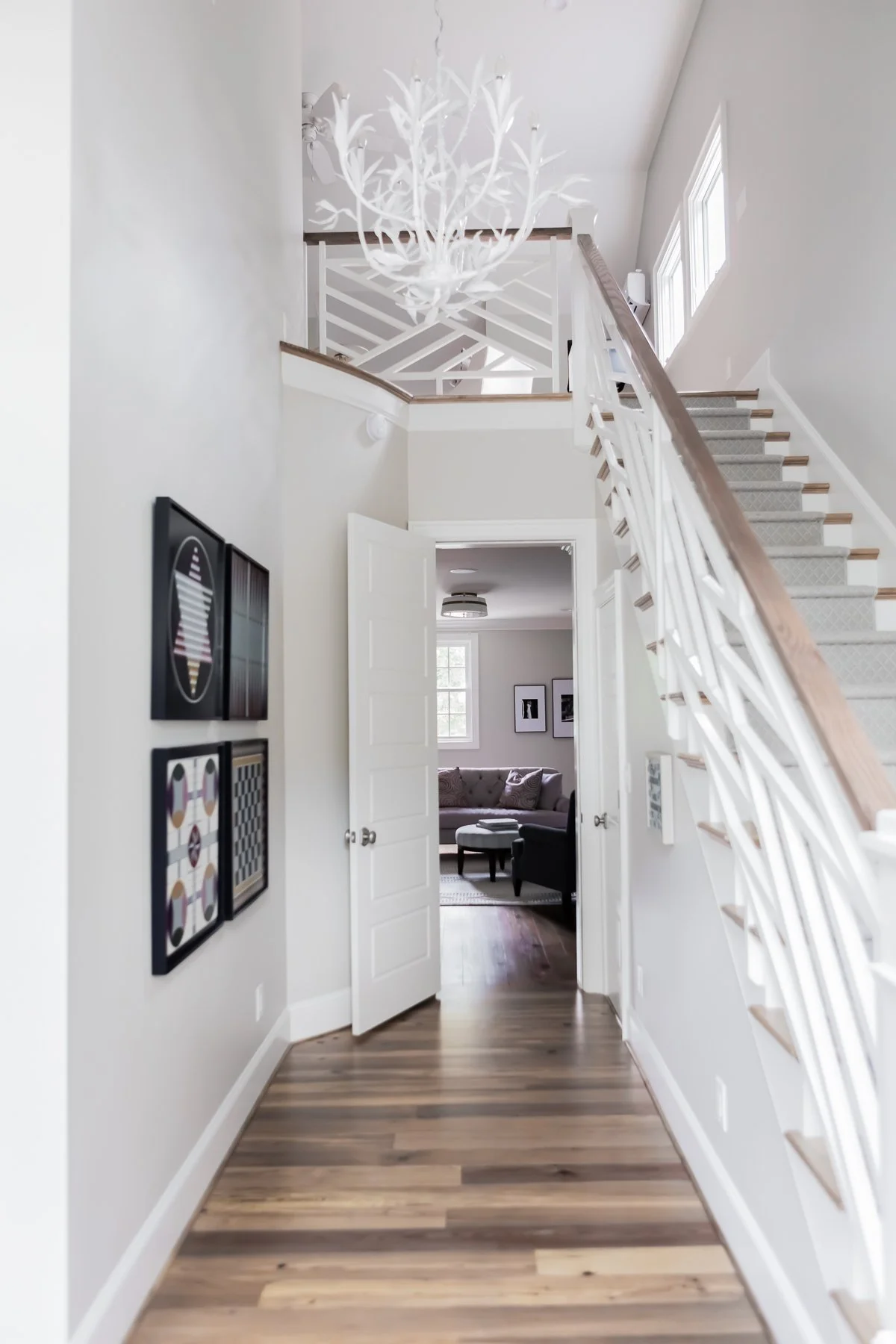 Staircase entryway in an Inside the Beltline custom home in Raleigh 27608 by Will Johnson Building Company featuring white railings, wood flooring, and clean architectural design