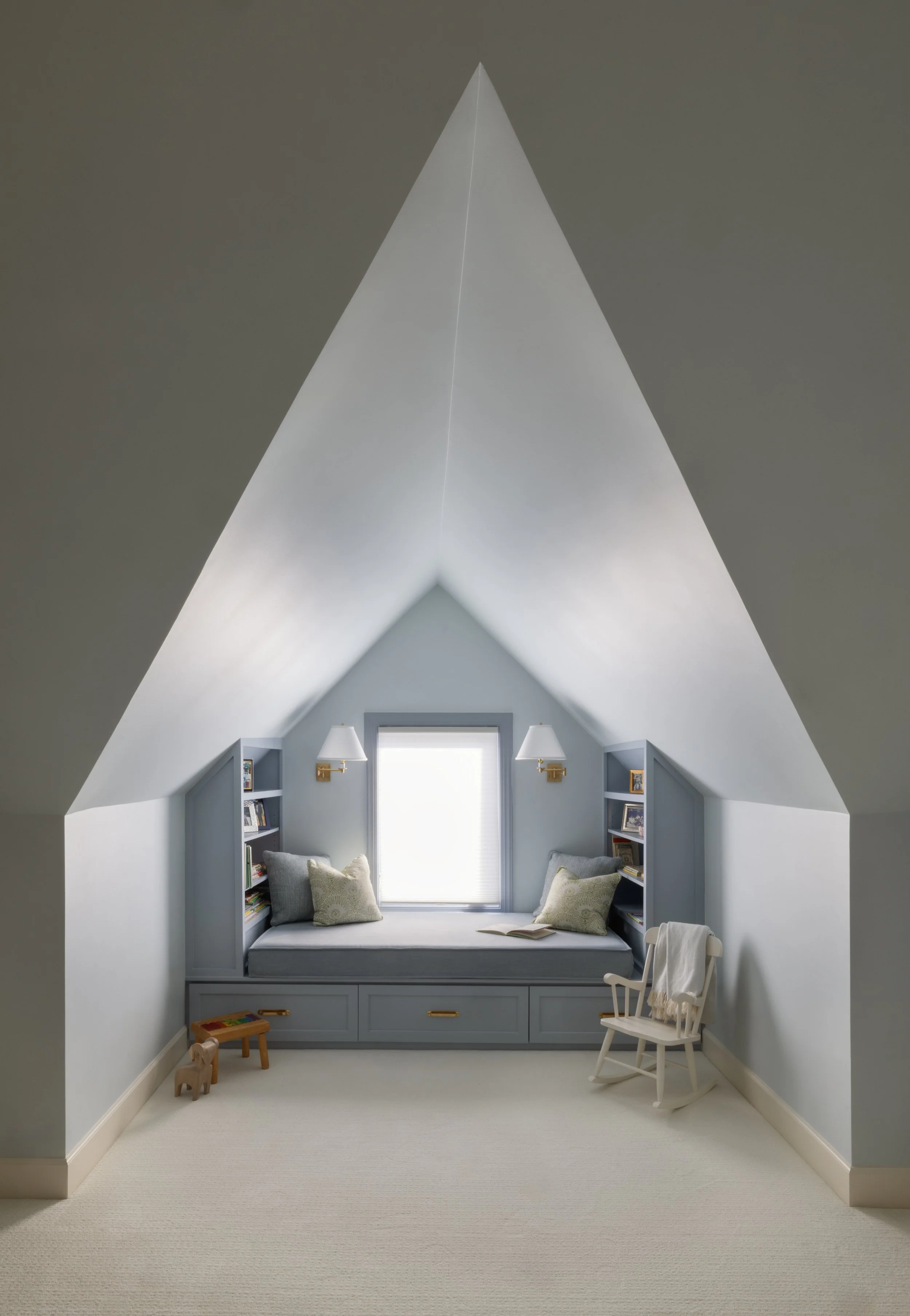 A cozy reading nook with a built-in window seat under a sloped ceiling, surrounded by small bookshelves, decorated with pillows, a book, and a rocking chair nearby.