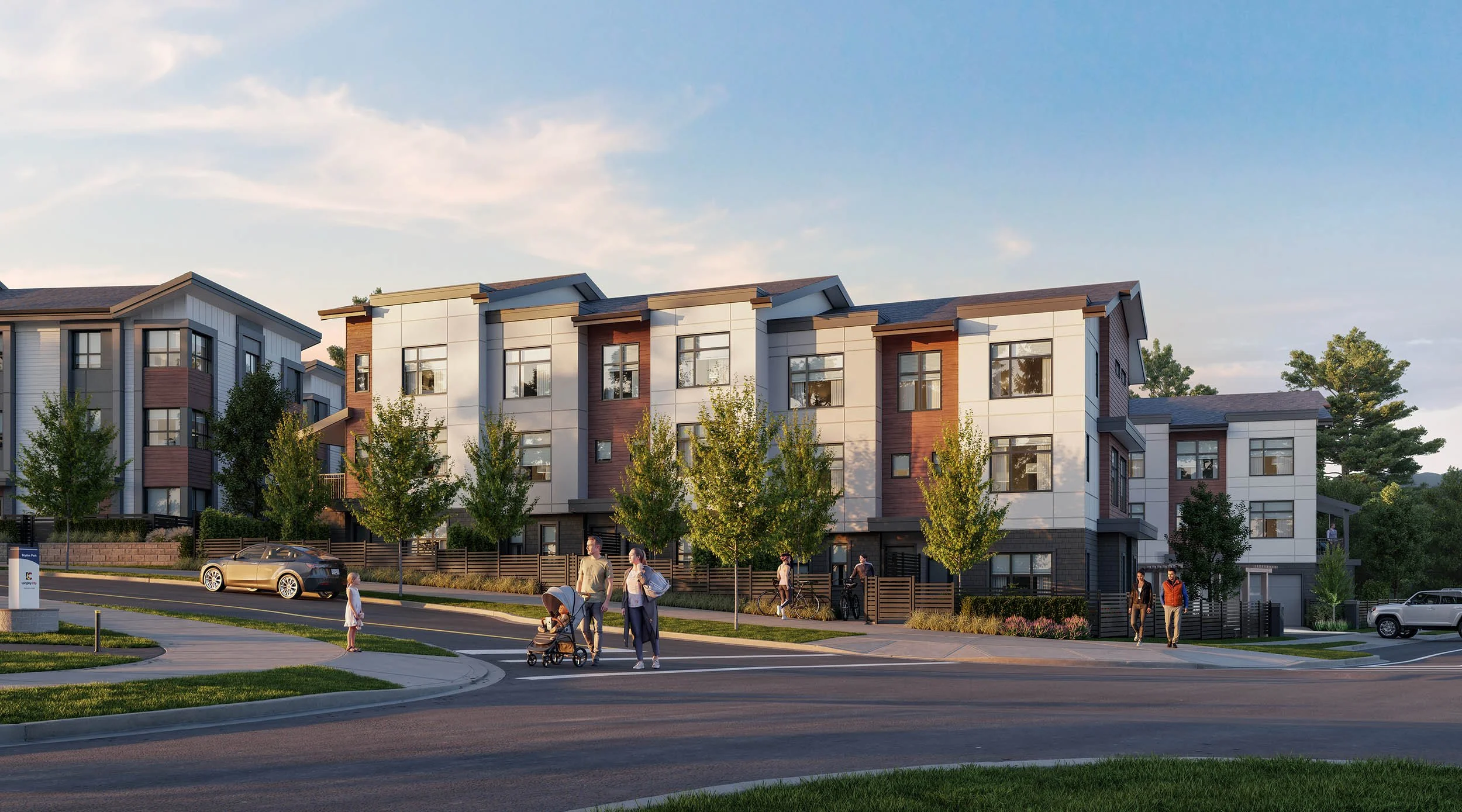 A shorter townhome block seen from a street corner in late afternoon light, with young trees, a parked car and residents walking along the sidewalk