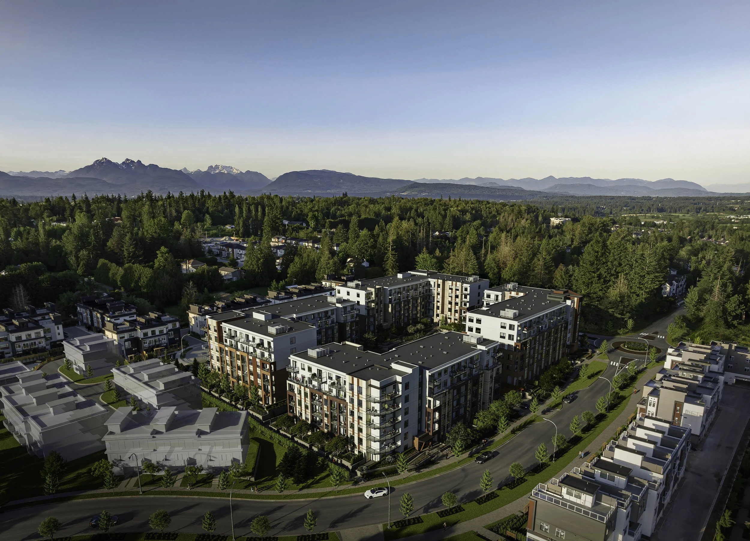 Aerial view of the development among townhomes and trees, with mountains on the horizon