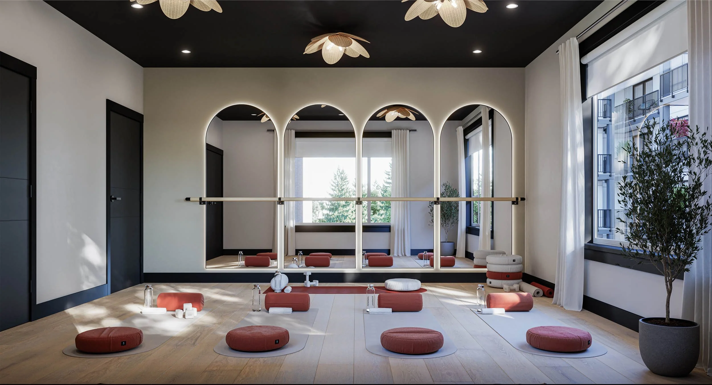 Yoga studio with arched mirrors, a ballet barre, a dark ceiling and cushions on a pale floor