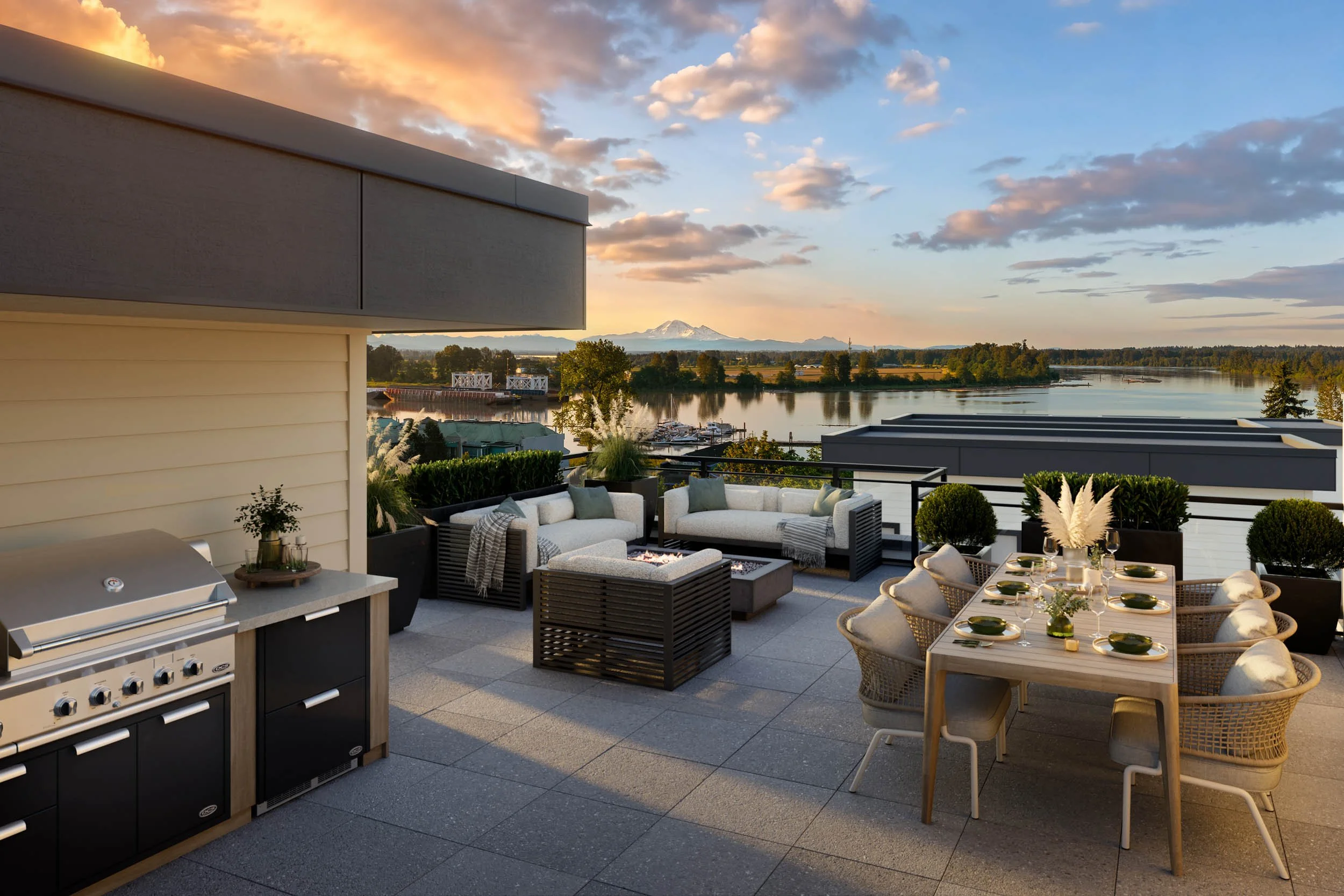 Rooftop terrace at sunset with a built-in grill, a lounge sectional and a dining table set for six, looking out over a river to distant mountains