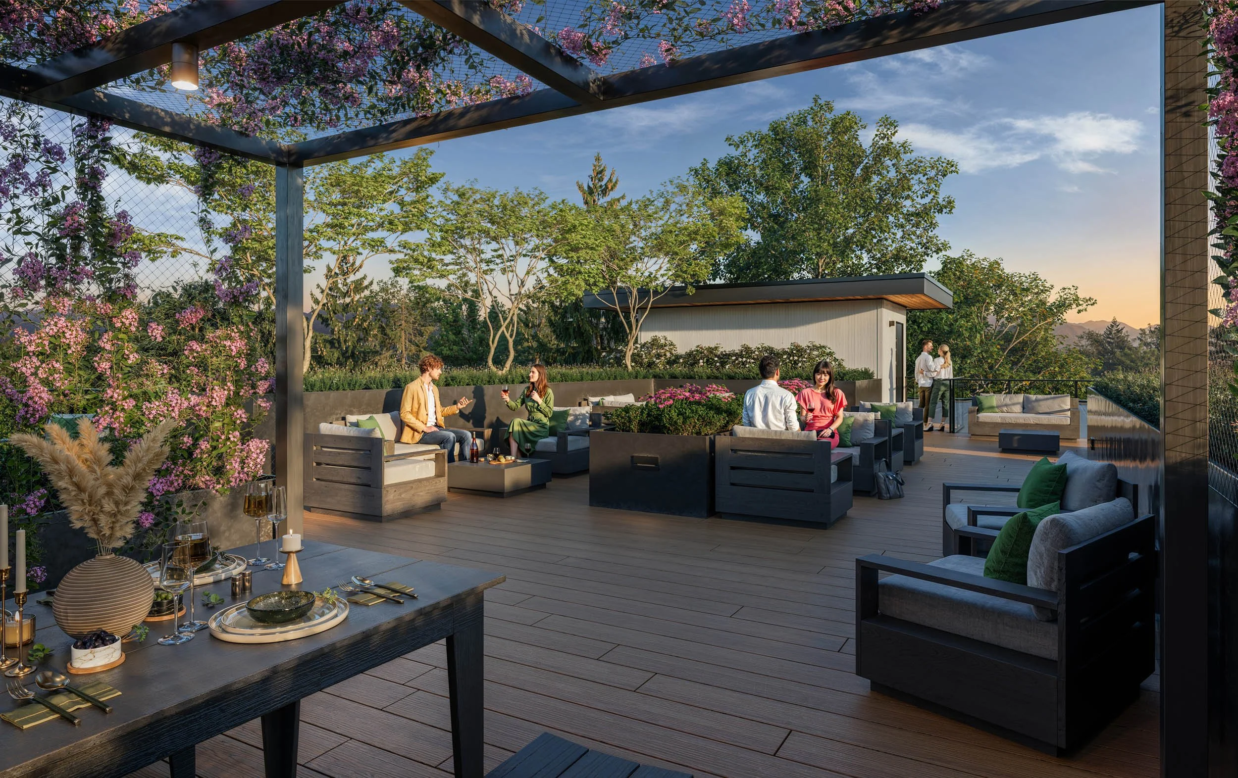Rooftop terrace at sunset under a planted pergola, with lounge seating, an outdoor dining table and residents talking, looking out over the treetops