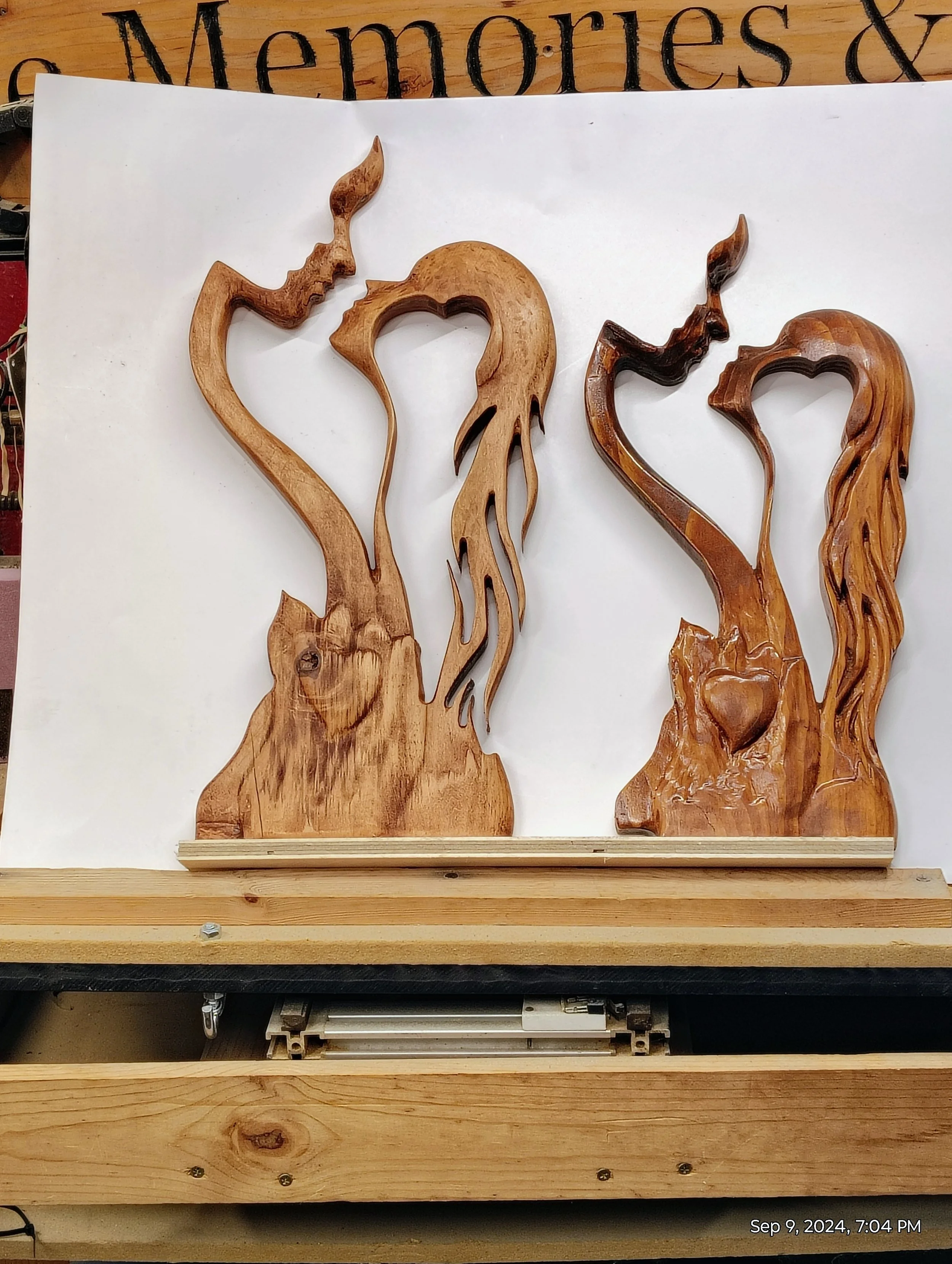 Wooden carvings of two abstract faces and figures on a white background