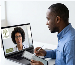 Man taking notes while participating in a virtual meeting with a woman on a laptop screen