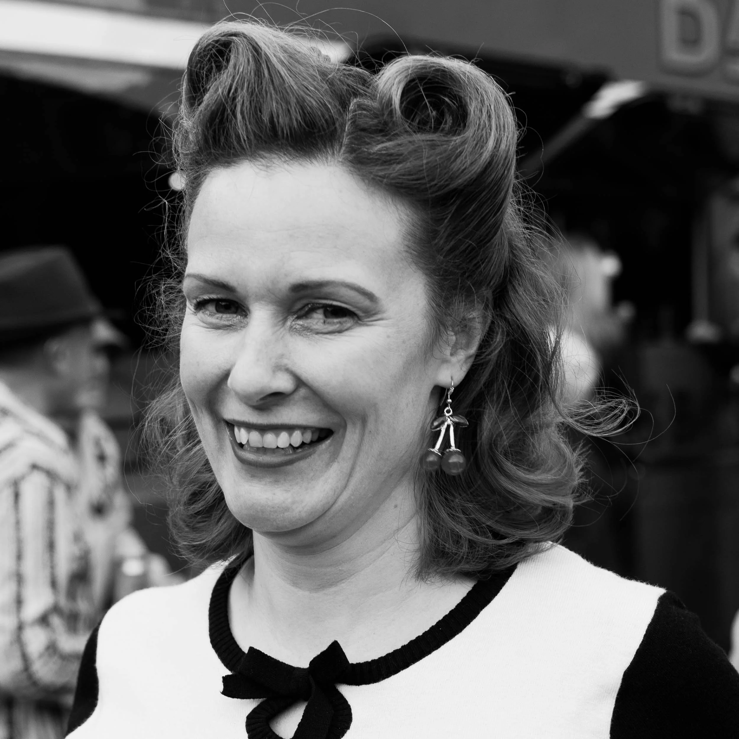 Street portrait of an attractive smiling woman with vintage era clothing, carefully curled and styled hair. Looking as if she has come from the 1950`s. black and white