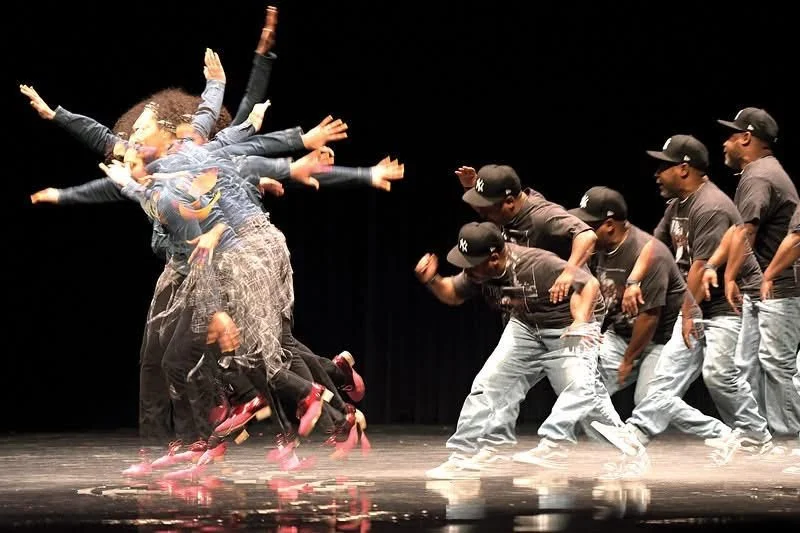 a stroboscopic photo of a black dancer moving her arms, with a black man in a ballcap behind her 