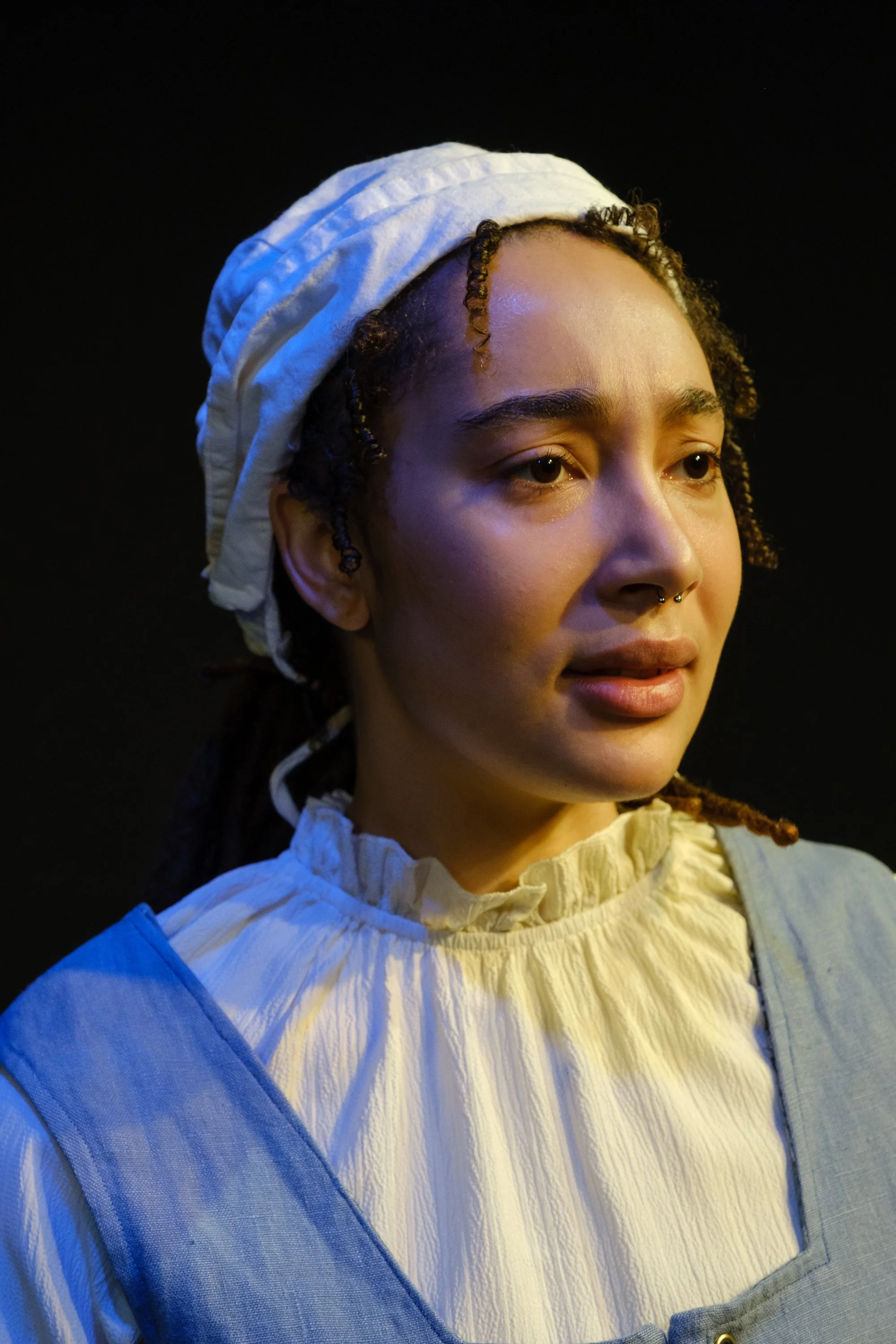 a young black woman in white cap and old fashioned clothes, her face expressing confusion or pain