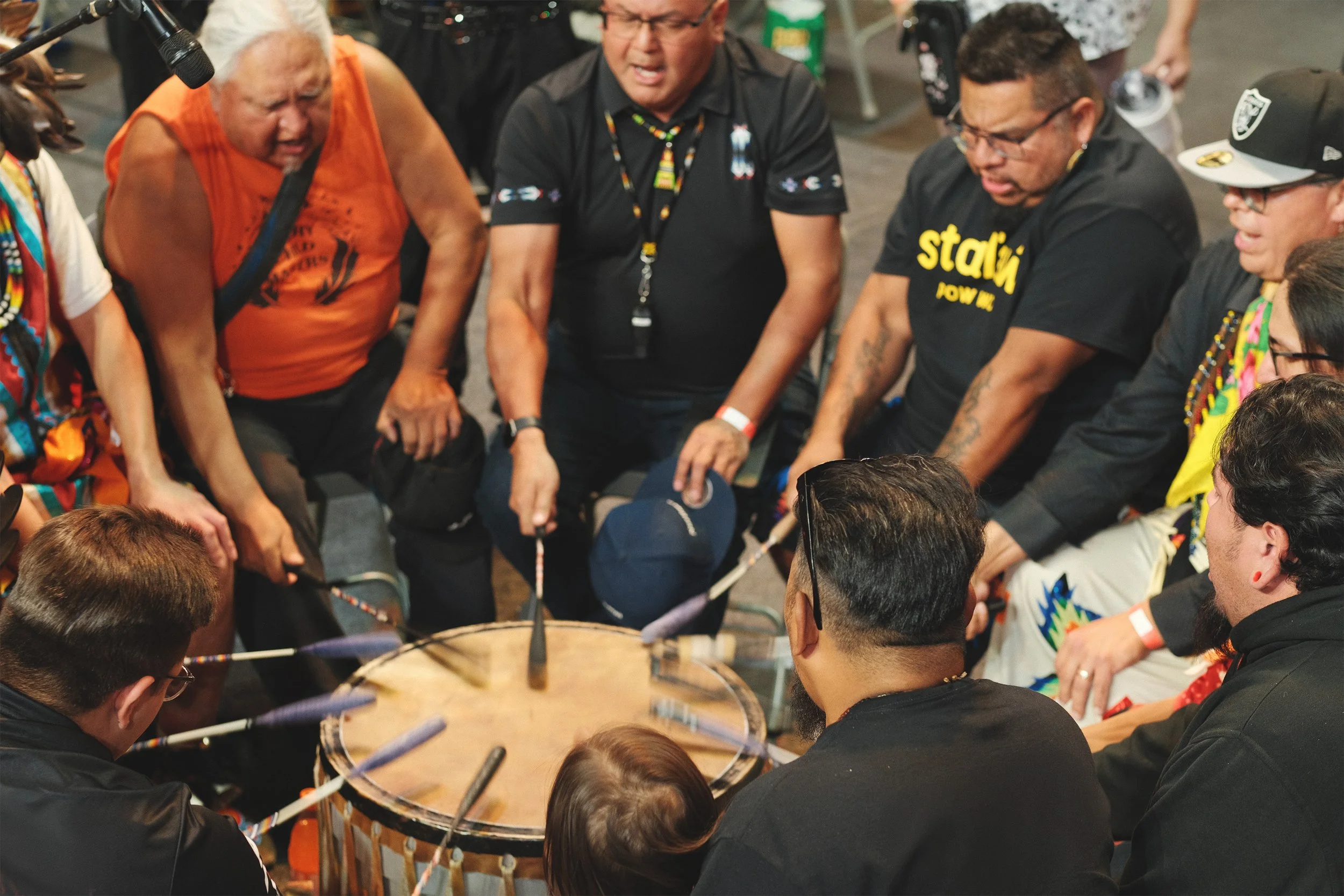 Group of people gathered around and playing a drum together at a cultural event.