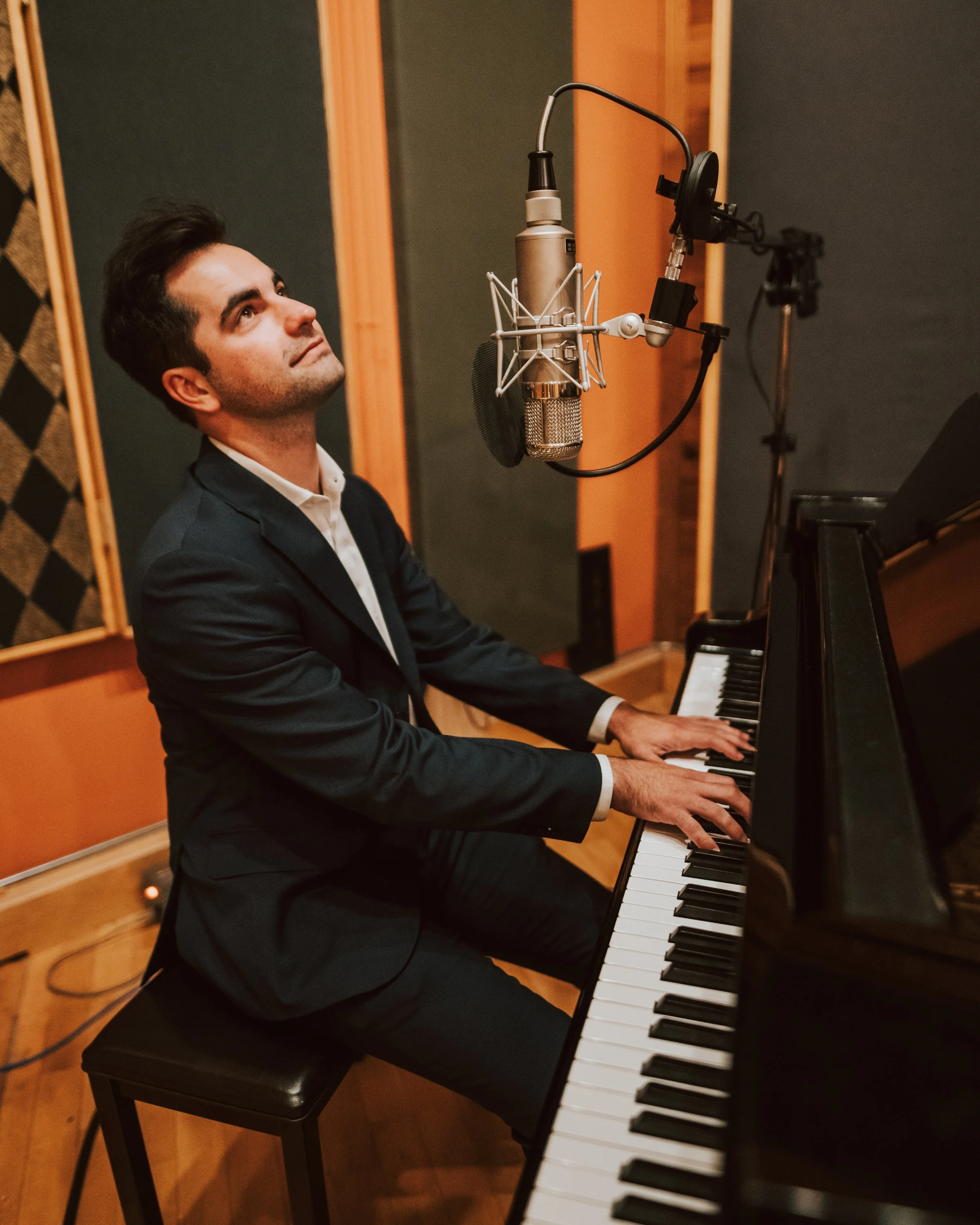 Matthew Zelenin playing a grand piano in a recording studio.