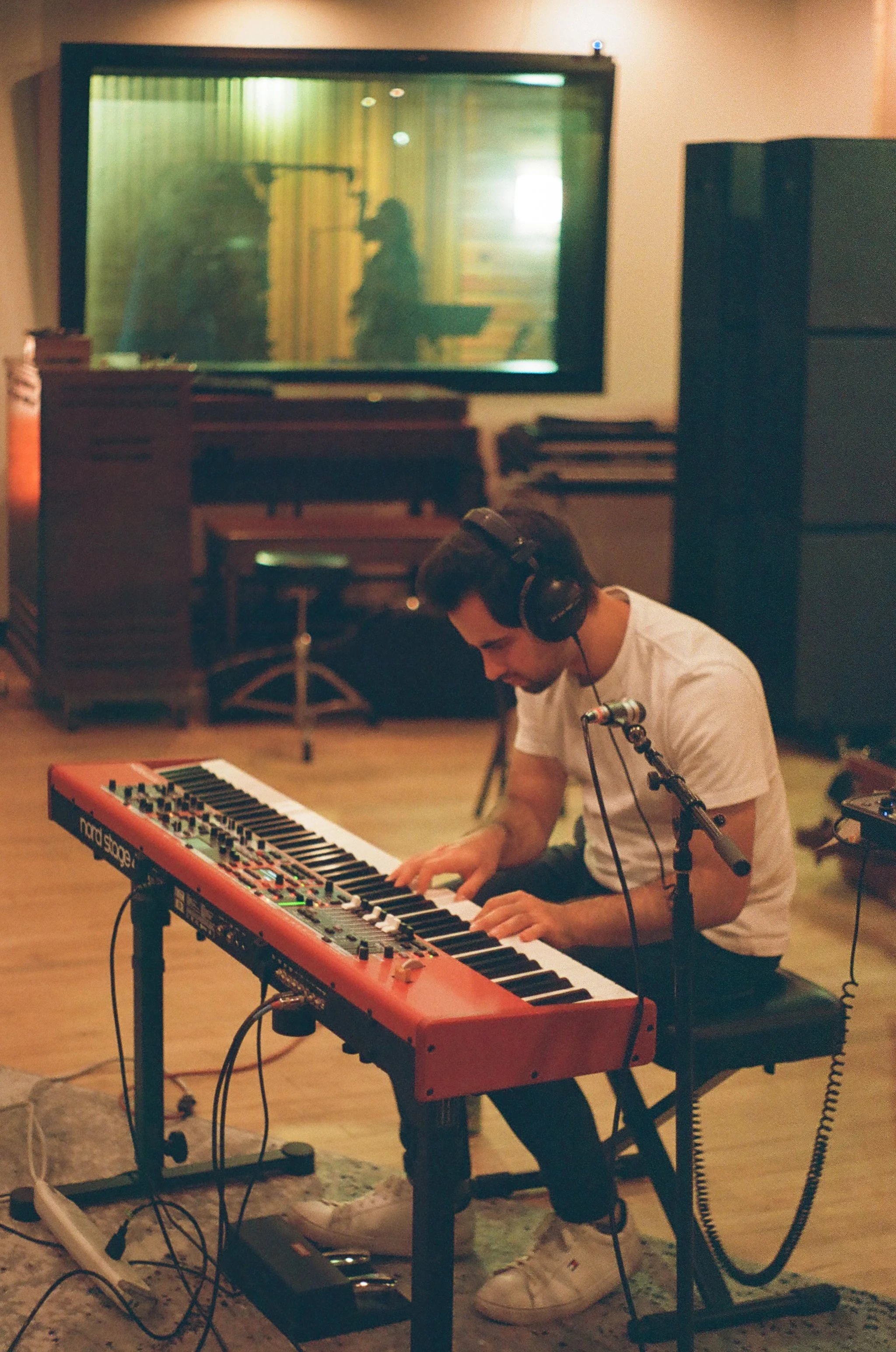 Matthew Zelenin playing a red Nord Stage keyboard in a recording studio.