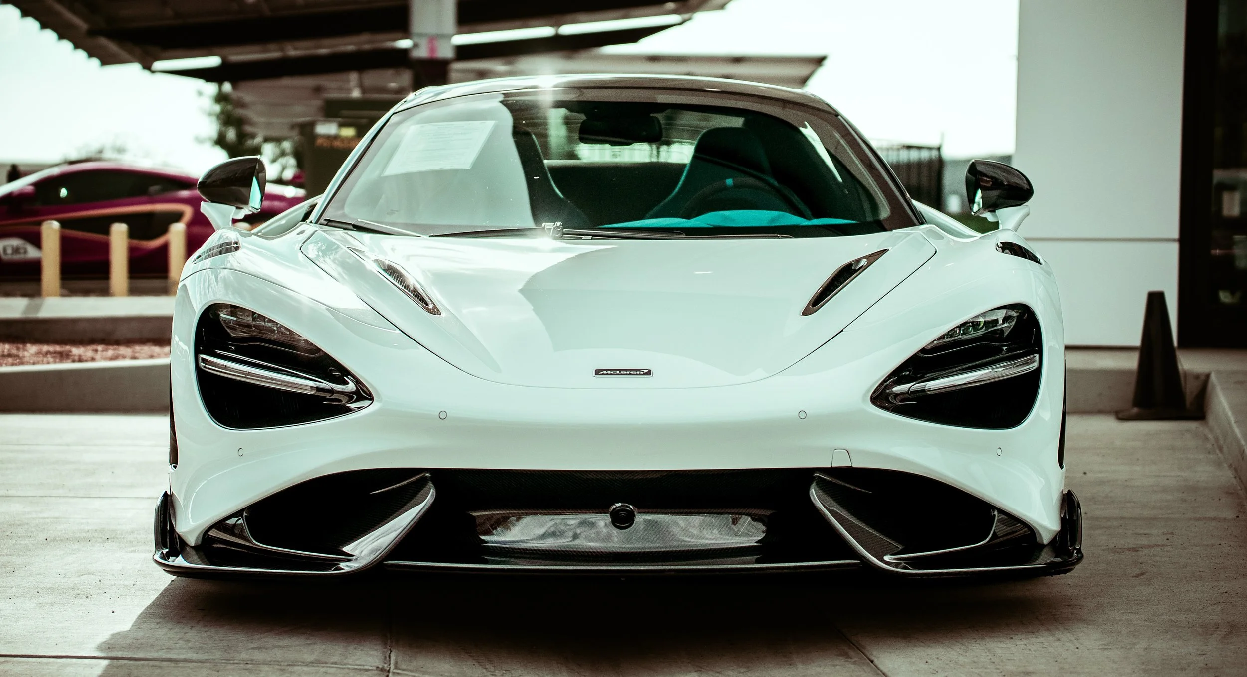 Front view of a white McLaren sports car parked in a lot.
