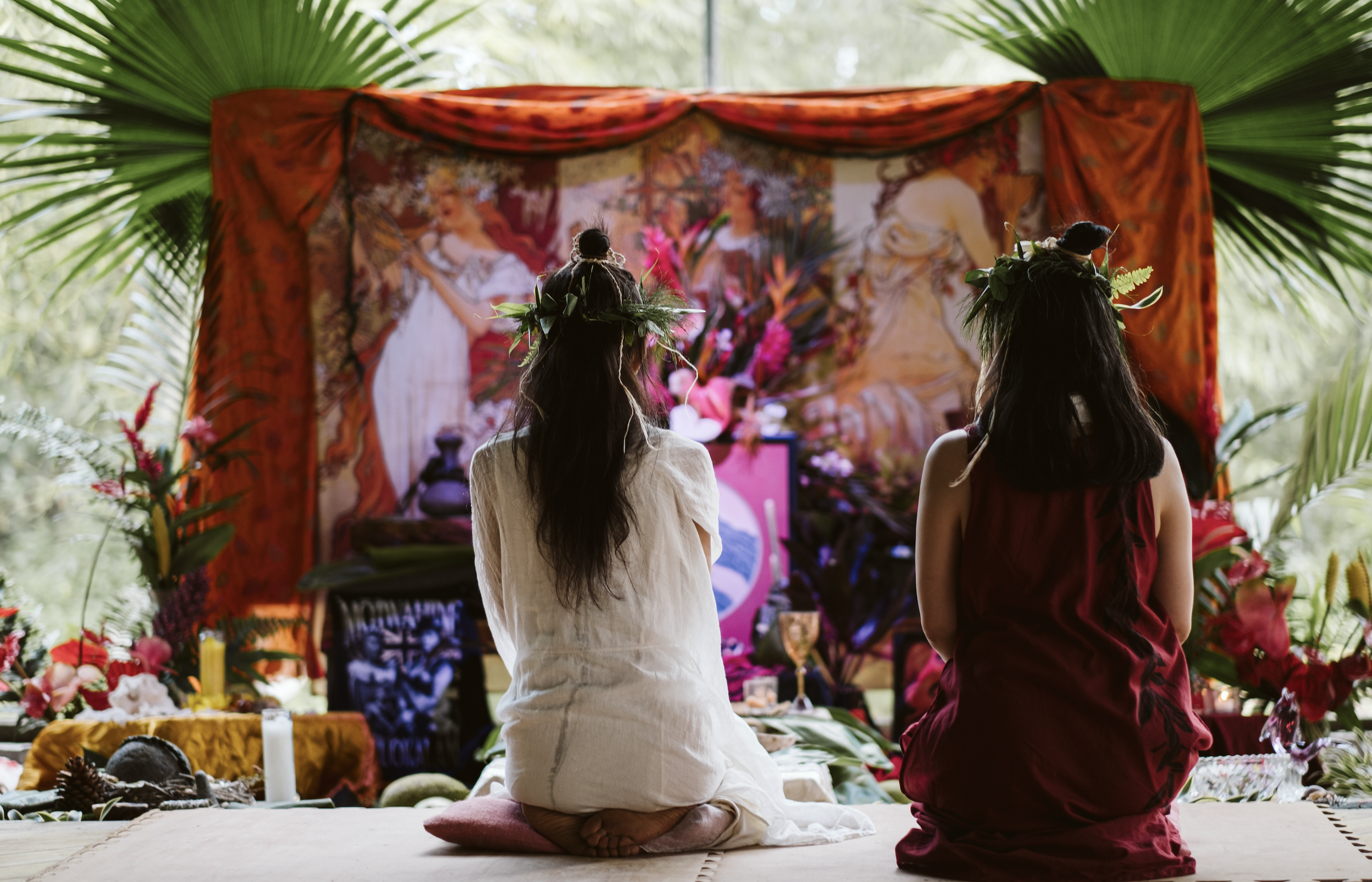 Two women kneel on the floor facing an altar at  ManaFest, a transformational music, dance, arts, and culture festival on Big Island of Hawaii 