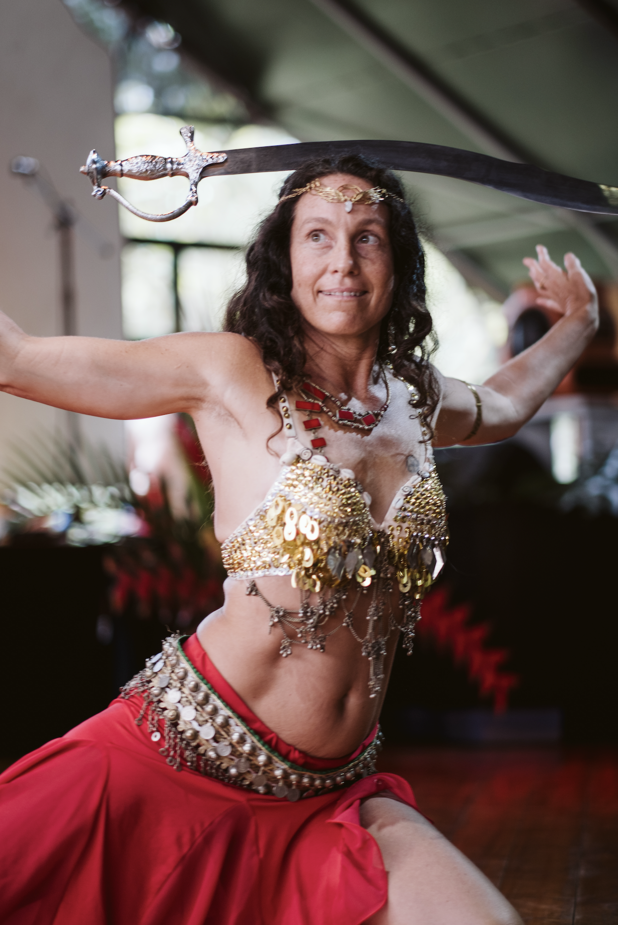 A woman dressed in a belly dance costume, performing a dance with a sword balanced on her head, at  ManaFest, a transformational music, dance, arts, and culture festival on Big Island of Hawaii 