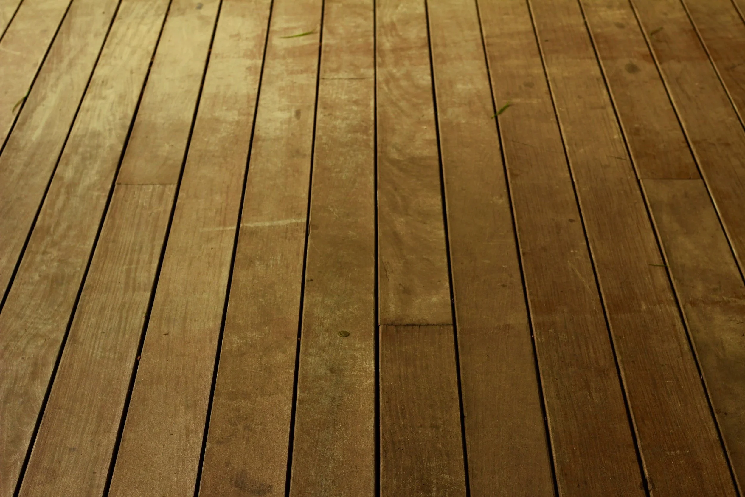 Close-up of wooden floorboards, showing grain and slight gaps between each plank.