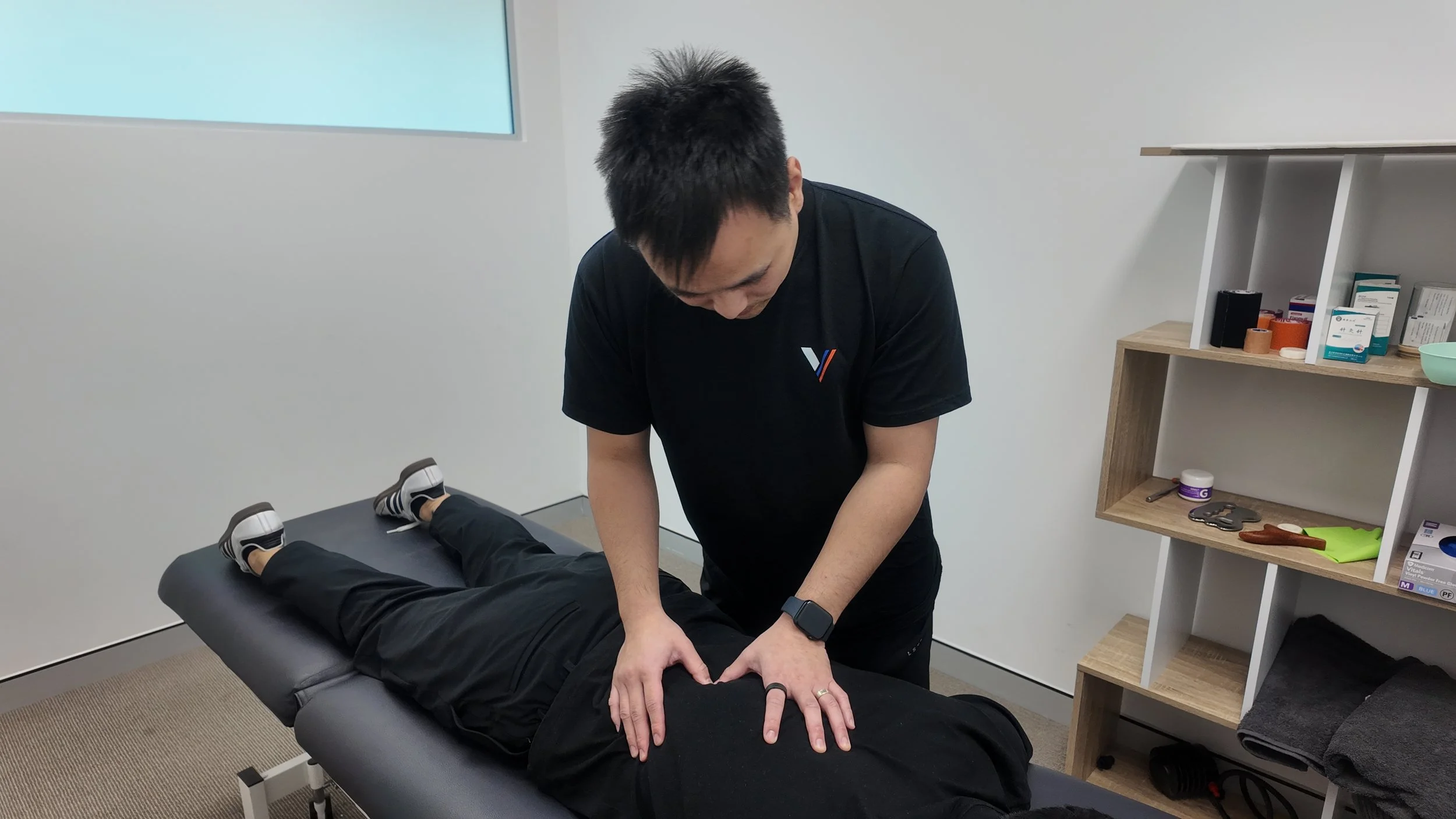 Physiotherapist David Woo treating a patient's lower back on a treatment table at Strive Sports and Health