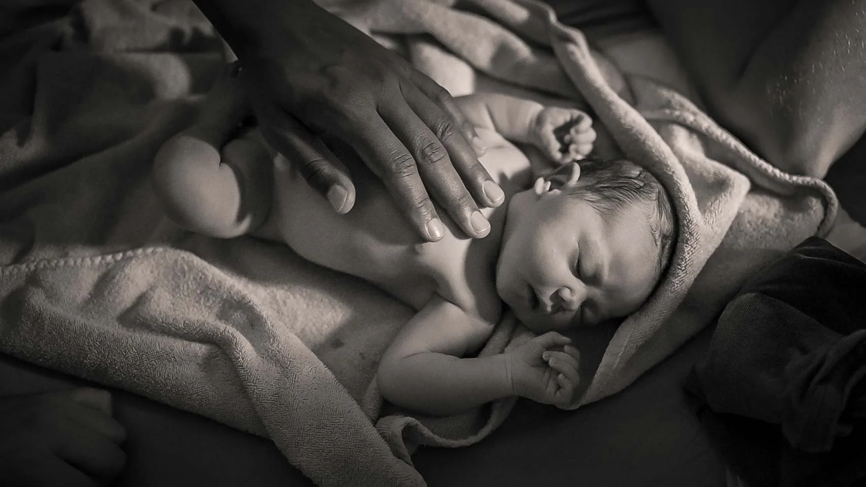 Geburtsbegleitung in Hamburg. Ein Neugeborenes Baby wird von seinem Vater gestreichelt.