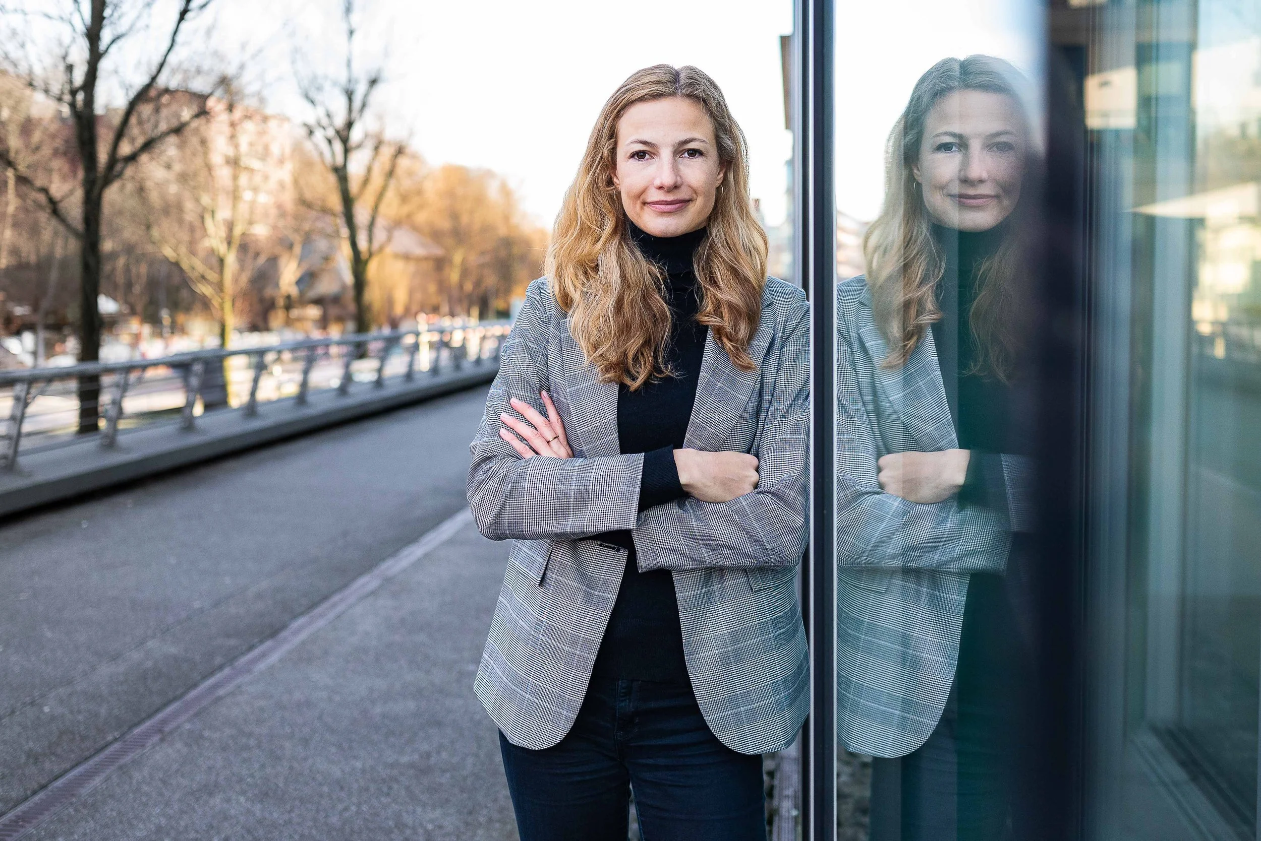Sympathisches Business Portrait einer blonden Frau in Hamburg, natürlich lächelnd vor urbanem Hintergrund.