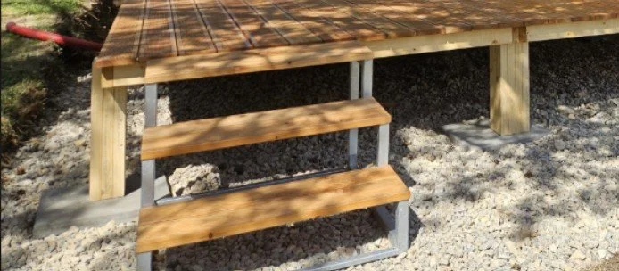 Holztreppe mit drei Stufen führt zu einer erhöhten Plattform.