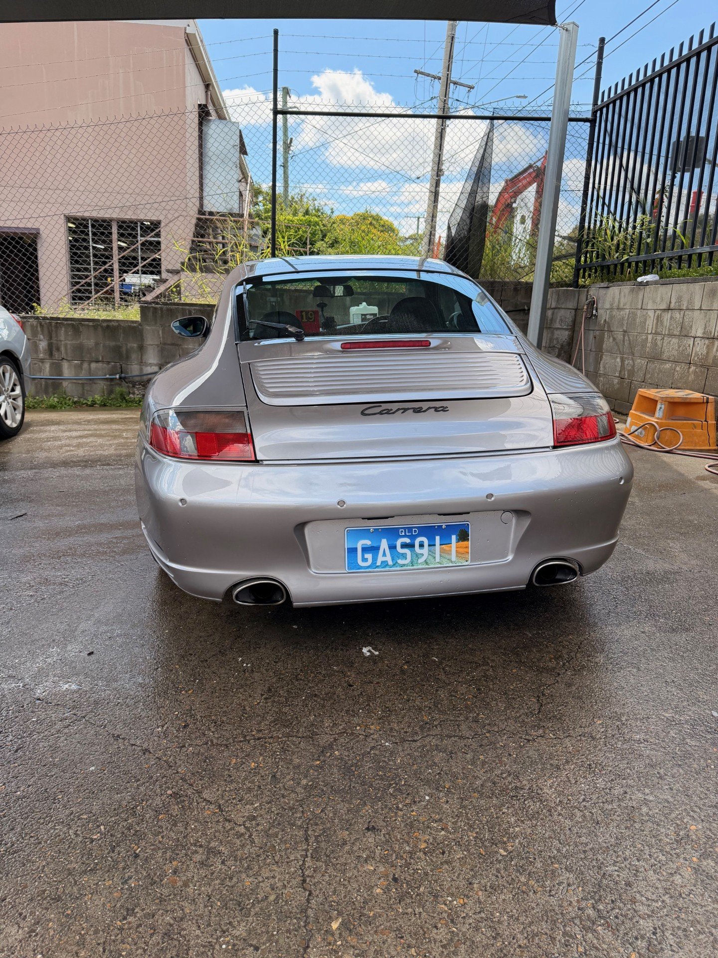 Silver Porsche Carrera parked outdoors with a Queensland license plate, showing the rear view.